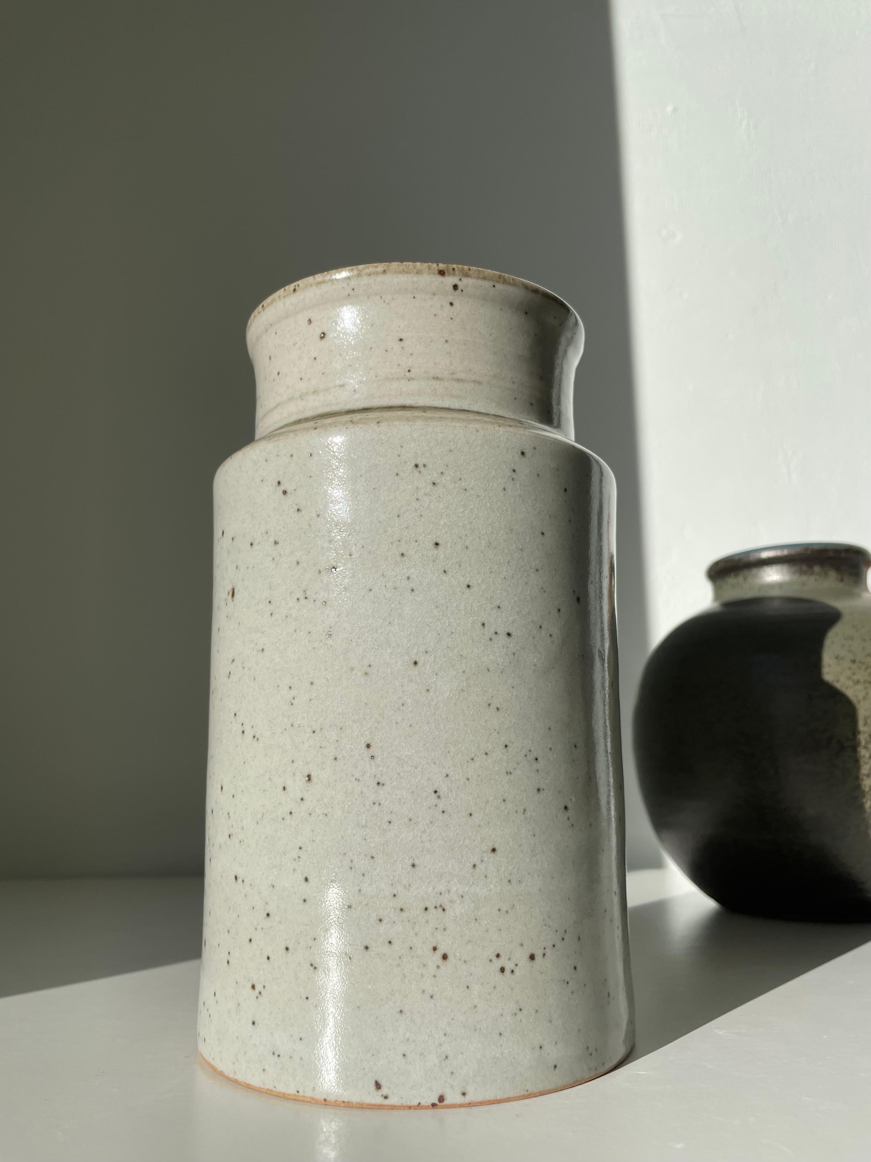 Stunning light gray, warm brown spotted shiny glaze on this classic Midcentury Modern large jar vase by ceramic artist Trude Barner Jespersen (1938-1997). Handmade, clean, functional cylinder shape in neutral earthtoned colors. Jespersen worked for
