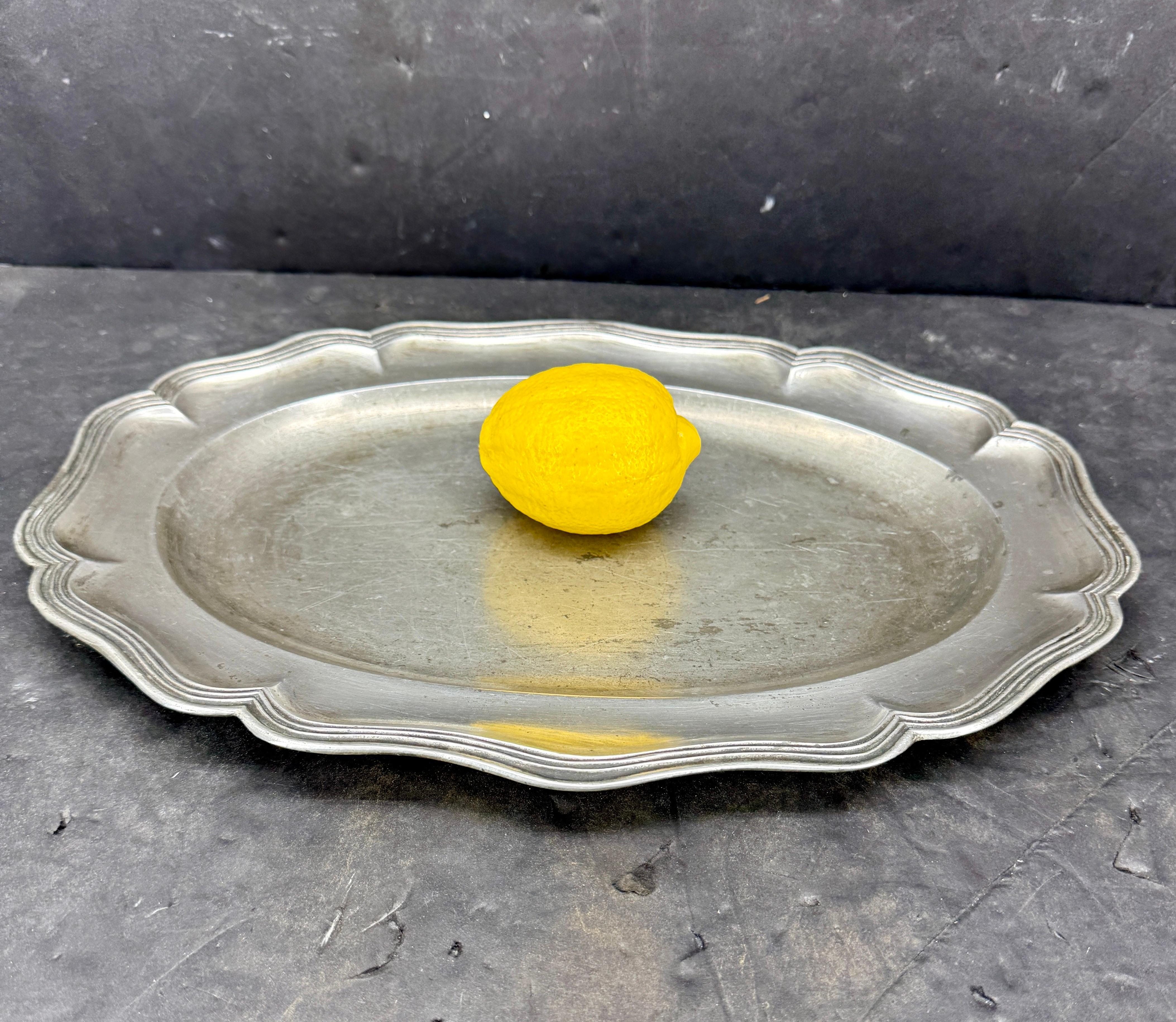 As found in Denmark, we see this large oval Rococo pewter tray being used for grapes and cheese with a nice bottle of wine by its side. Unbeatable wear and patina. Very charming piece to add to a collection. 
The tray has a vintage plate bracket