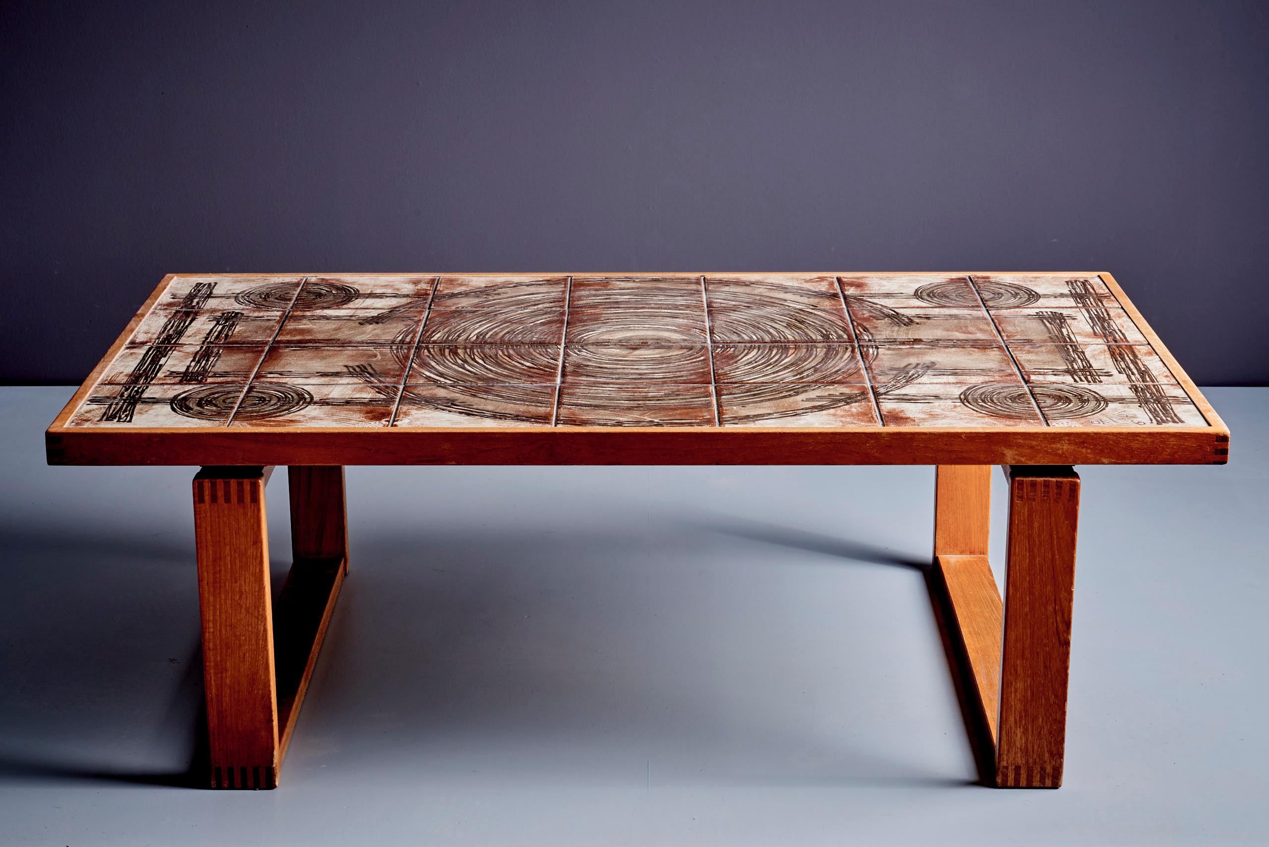 Couchtisch mit Keramikfliesen mit kreisförmigem Muster. Der Sockel ist aus massivem Teakholz gefertigt und weist schöne Tischlerarbeiten auf. Das Design ist mit 