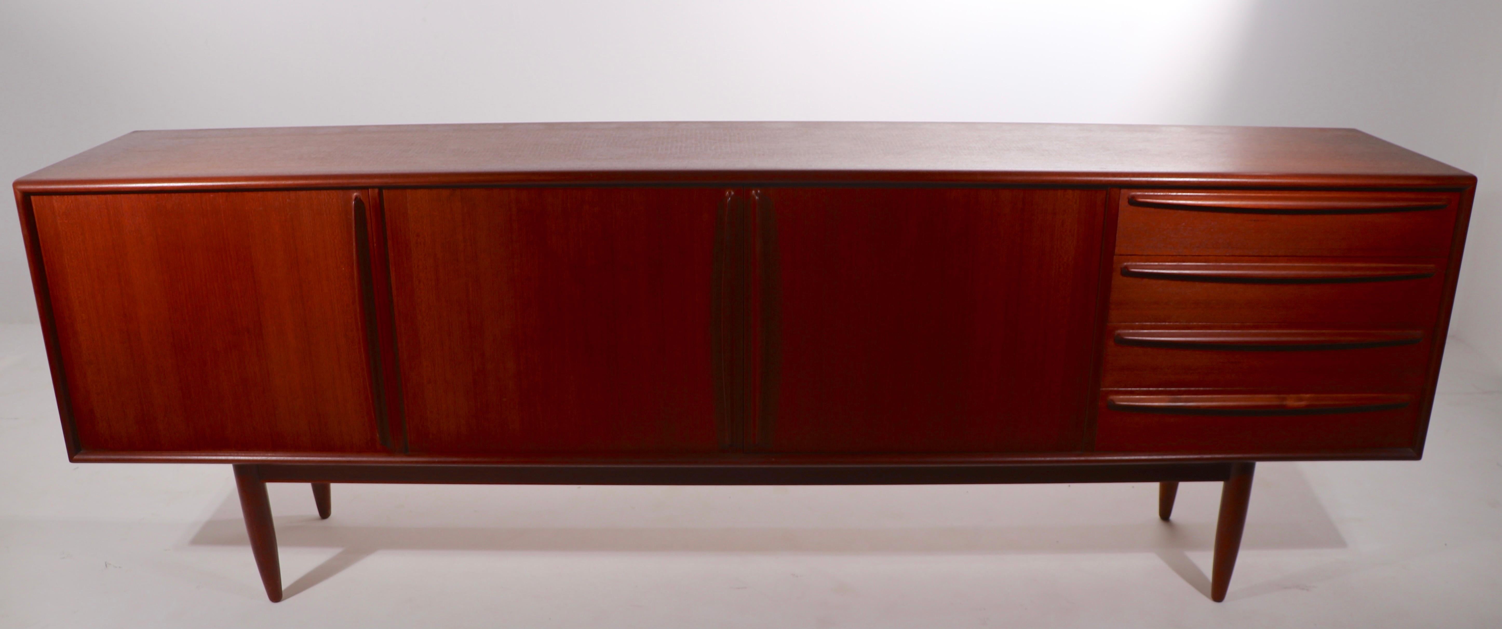 Spectacular large (95.75 in W) Danish modern sideboard, dry bar, credenza. This example features a bank of our drawers which flank two center doors, which open to shelved storage, and a fourth door that opens to a dry bar cabinet. The credenza is in