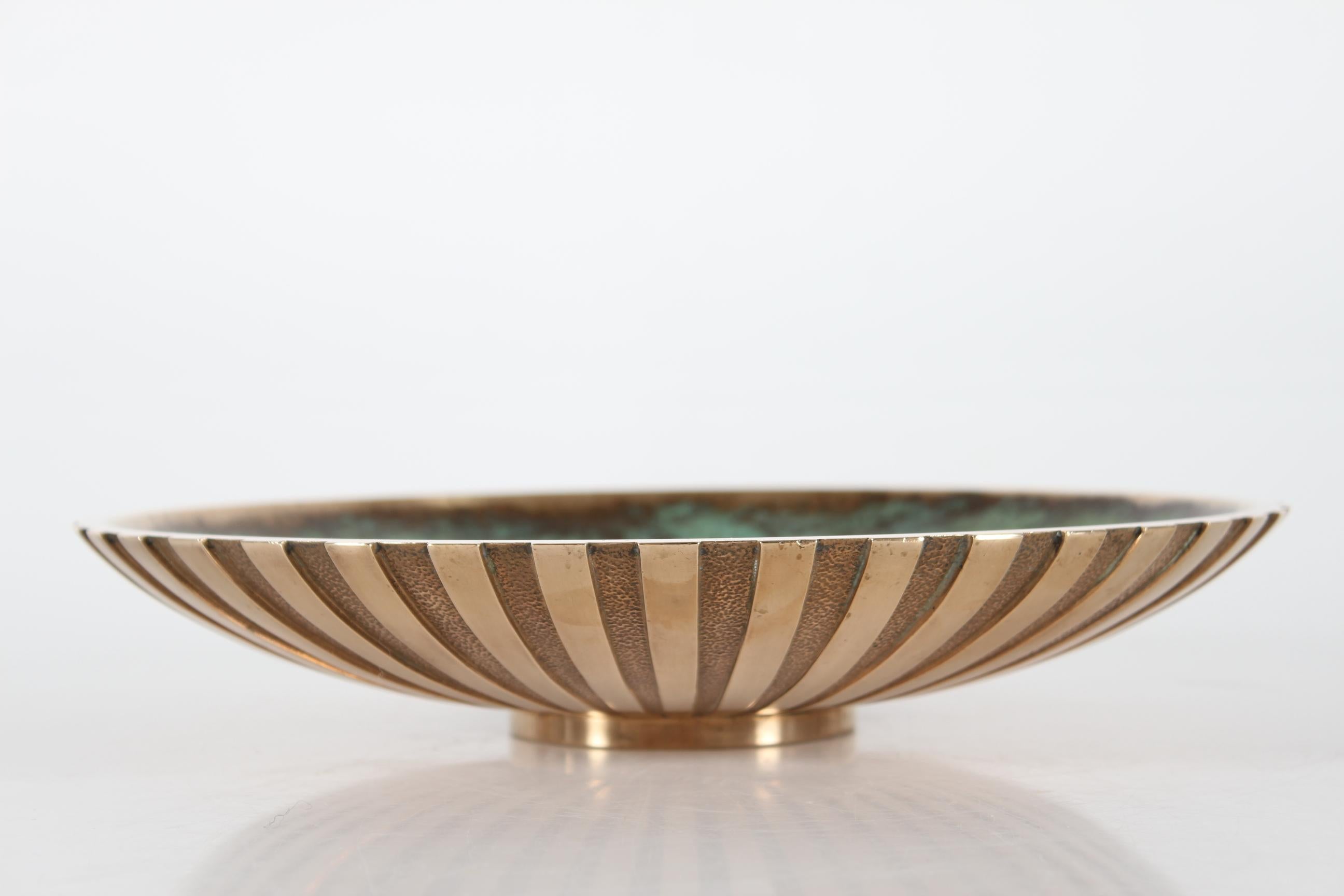 Tinos Art Deco heavy bronze dish with outstanding verdigris green patina made in Denmark 1940-50.
The back of the dish has a fluted radiating decoration in bronze.

Stamped: Tinos + ægte bronce (genuine bronze) + Made in Denmark

Very nice vintage