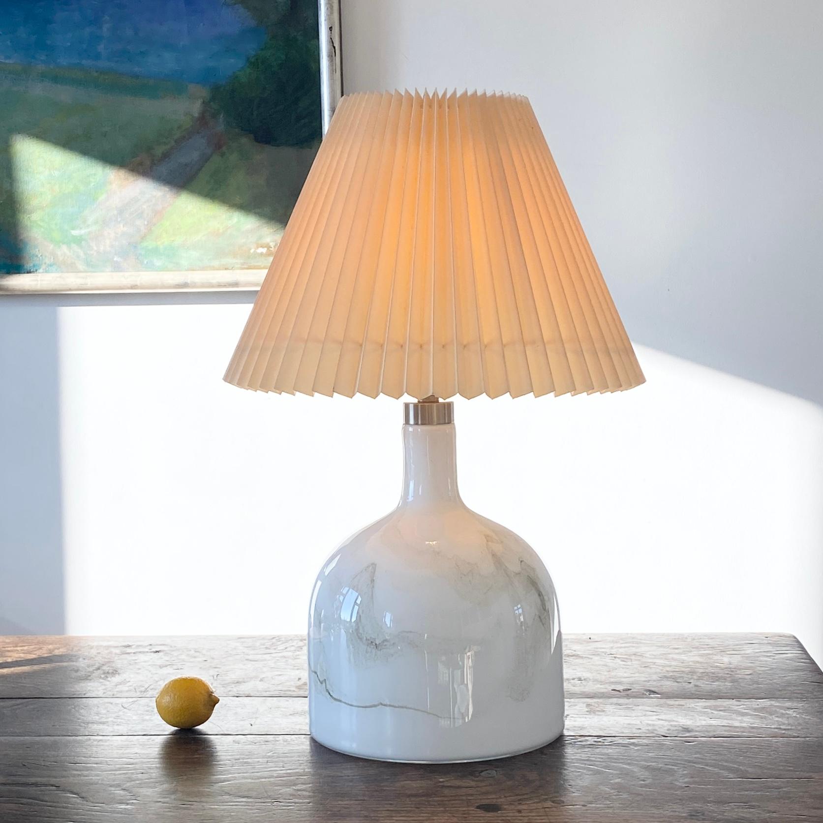 Dänische Sakura Holmegaard Tischlampe von Michael Bang für Holmegaard.
Die Tischleuchte Sakura ist aus dickem weißem und grauem Opalglas gefertigt. Die Leuchte besteht aus geschmolzenem Glas, das unter dem glatten, klaren Glas verwirbelt ist. Sie