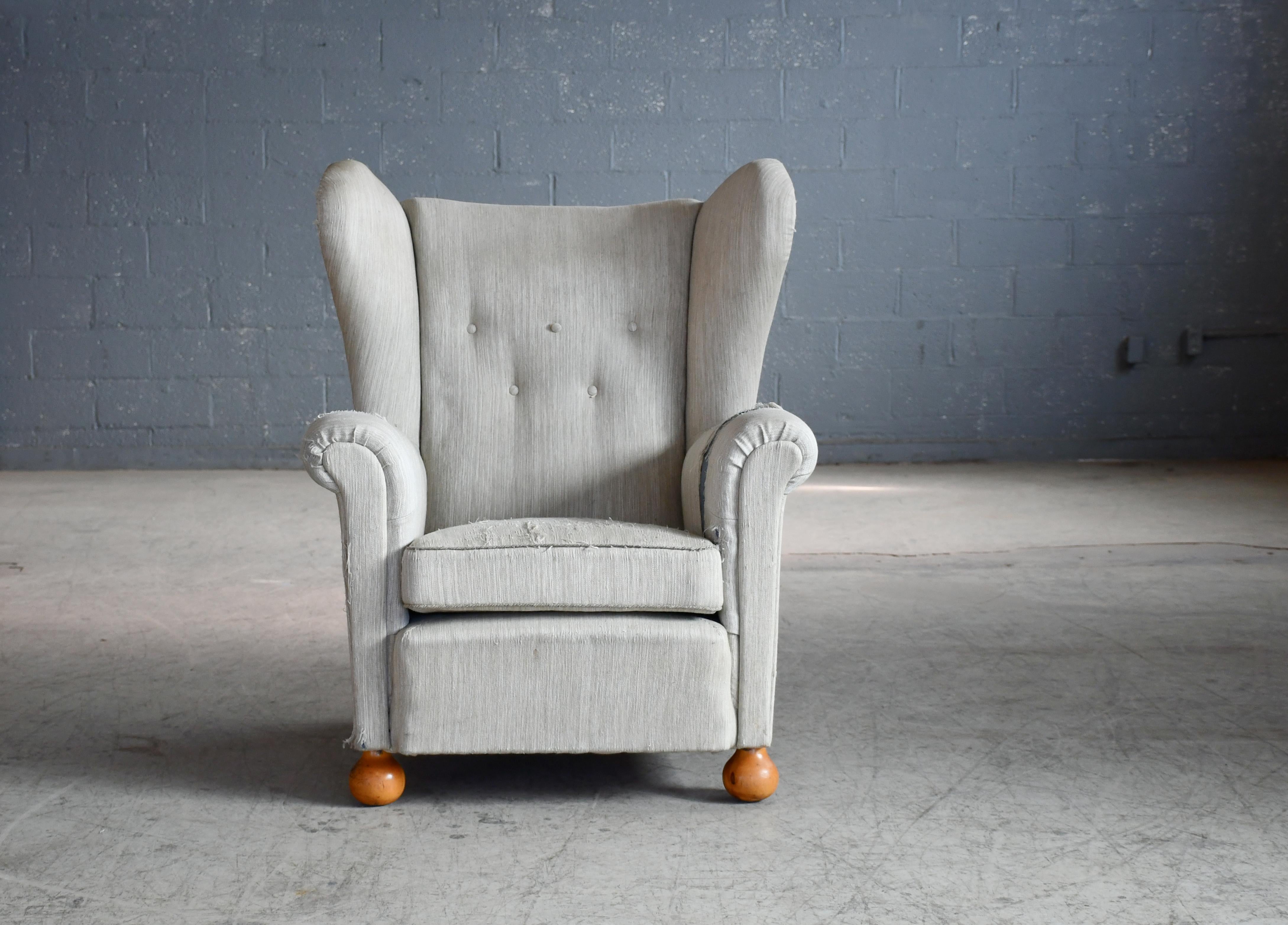 Fantastic Danish 1940s large scale wingback armchair. We love the sharp yet refined lines. Very comfortable with spring coils in seat cushion and backrest raised on beech wood legs.  Large presence and strong statement piece. The fabric is showing