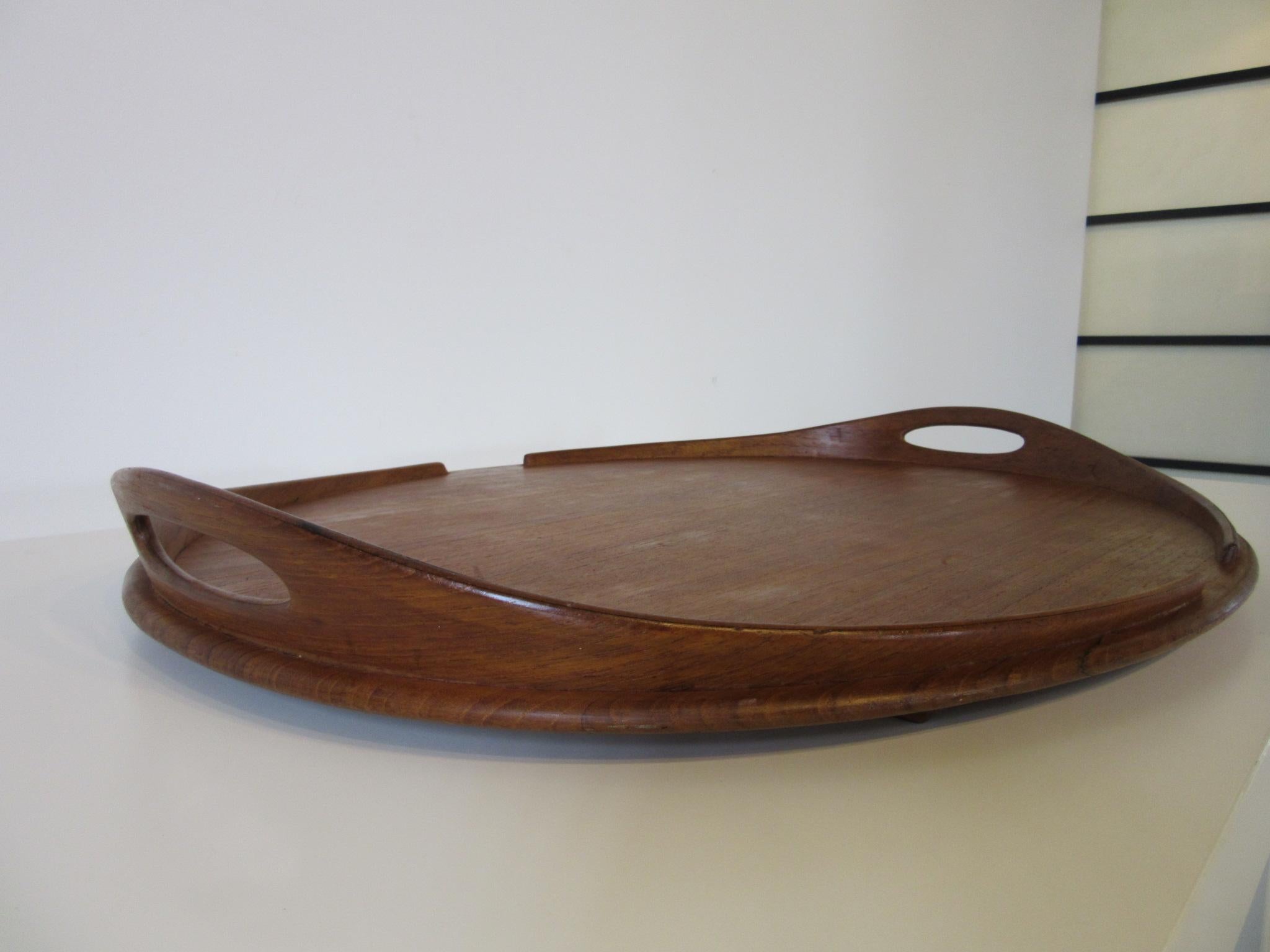 A very large and wonderful teak wood tray with sculptural handles and edge trim, the bottom has runners and is branded Dansk Denmark with the four ducks mark making this a early production piece from the manufacturer.