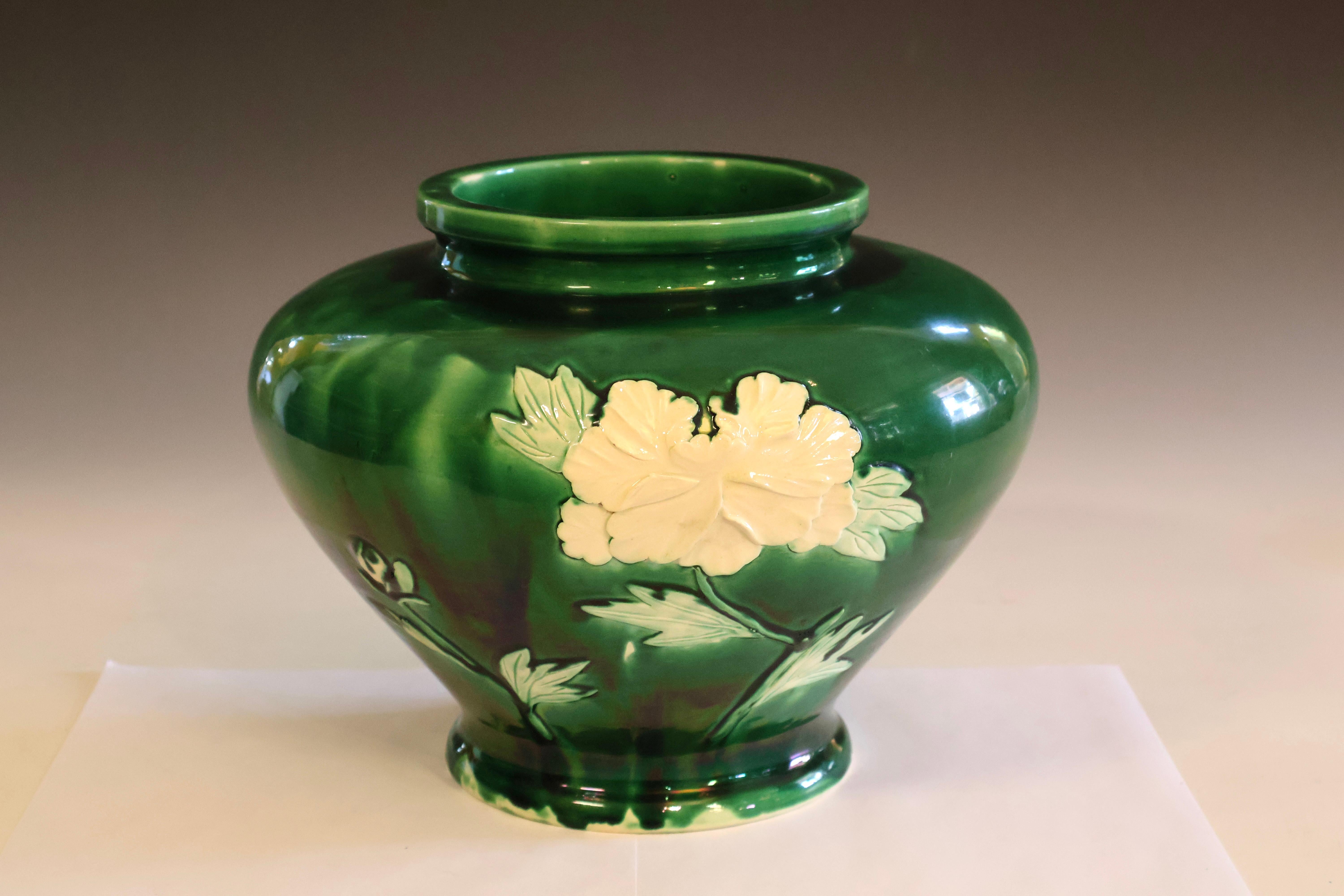 Large and stoutly potted Danto-Awaji pottery vase with sprigged white peony designs standing out in stark relief against a dark green glaze. Arresting form, inspired by a traditional bronze shape, with thick, articulated mouthrim and exaggerated
