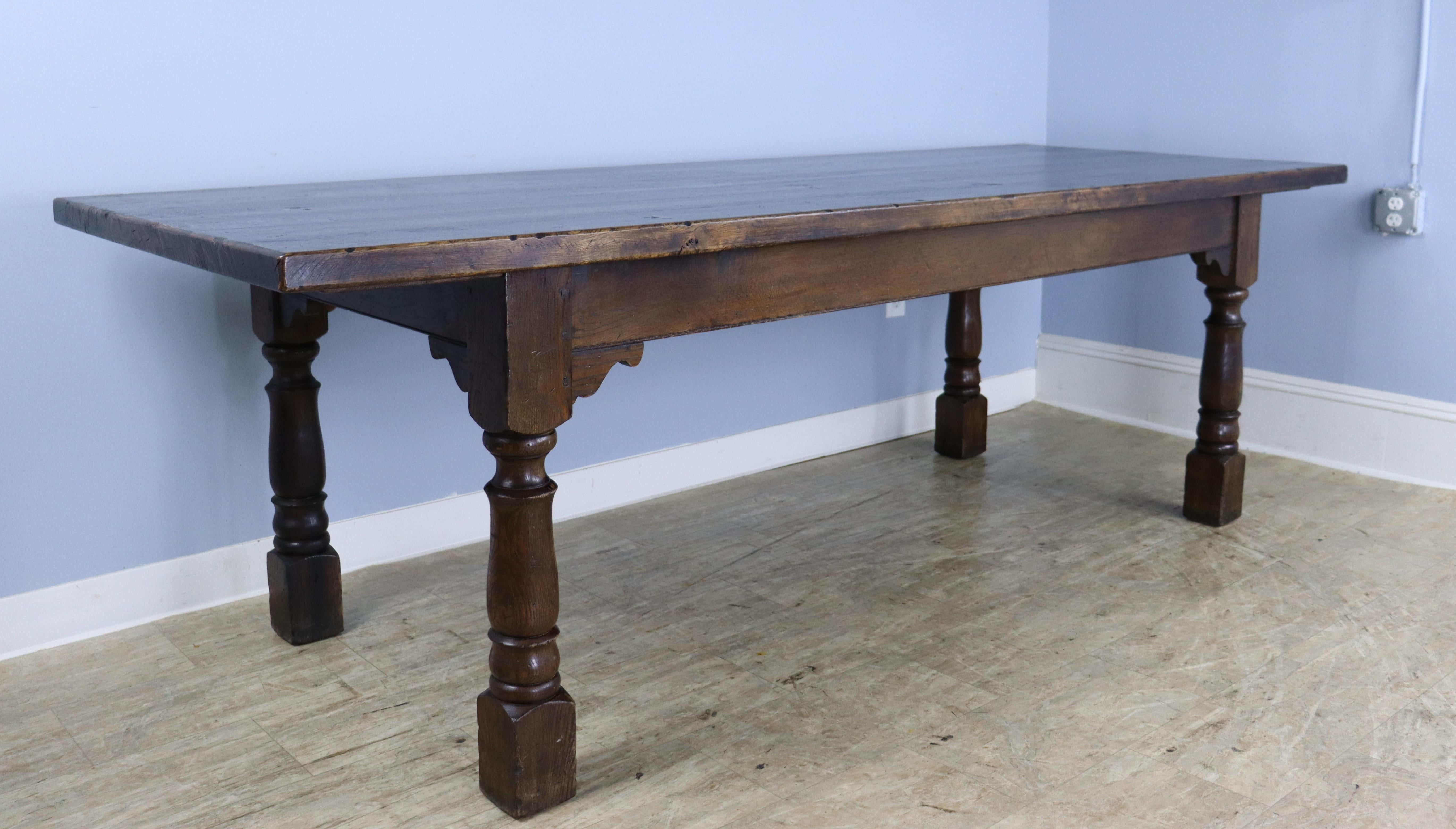 A generously proportioned almost 8' dark farm table with a thick top. The top has good texture, and the turned legs at the base add a note of grandeur. Good depth for family dining . The 24 inch apron height is good for knees, and there are 65