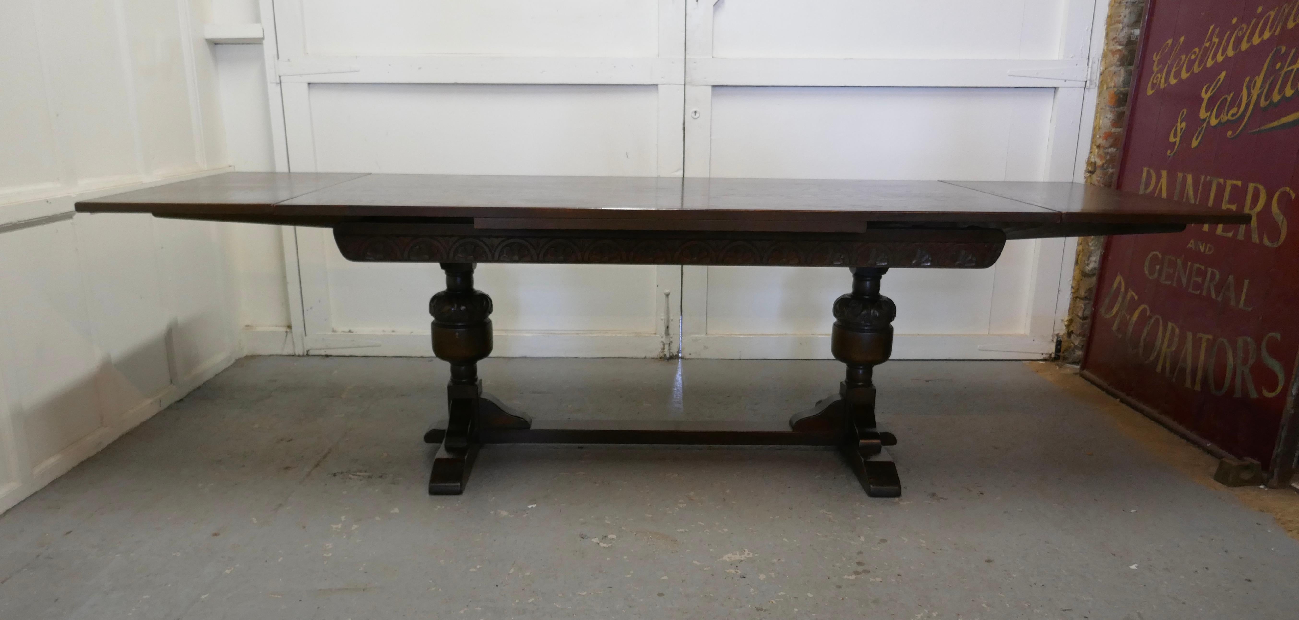 Large dark oak refectory extending table

This is a good large table, it has a 1” thick oak top, the table top is cleated at both ends as are the leaves 
The legs are in the refectory style carved with a bulbous column and a floor stretcher the