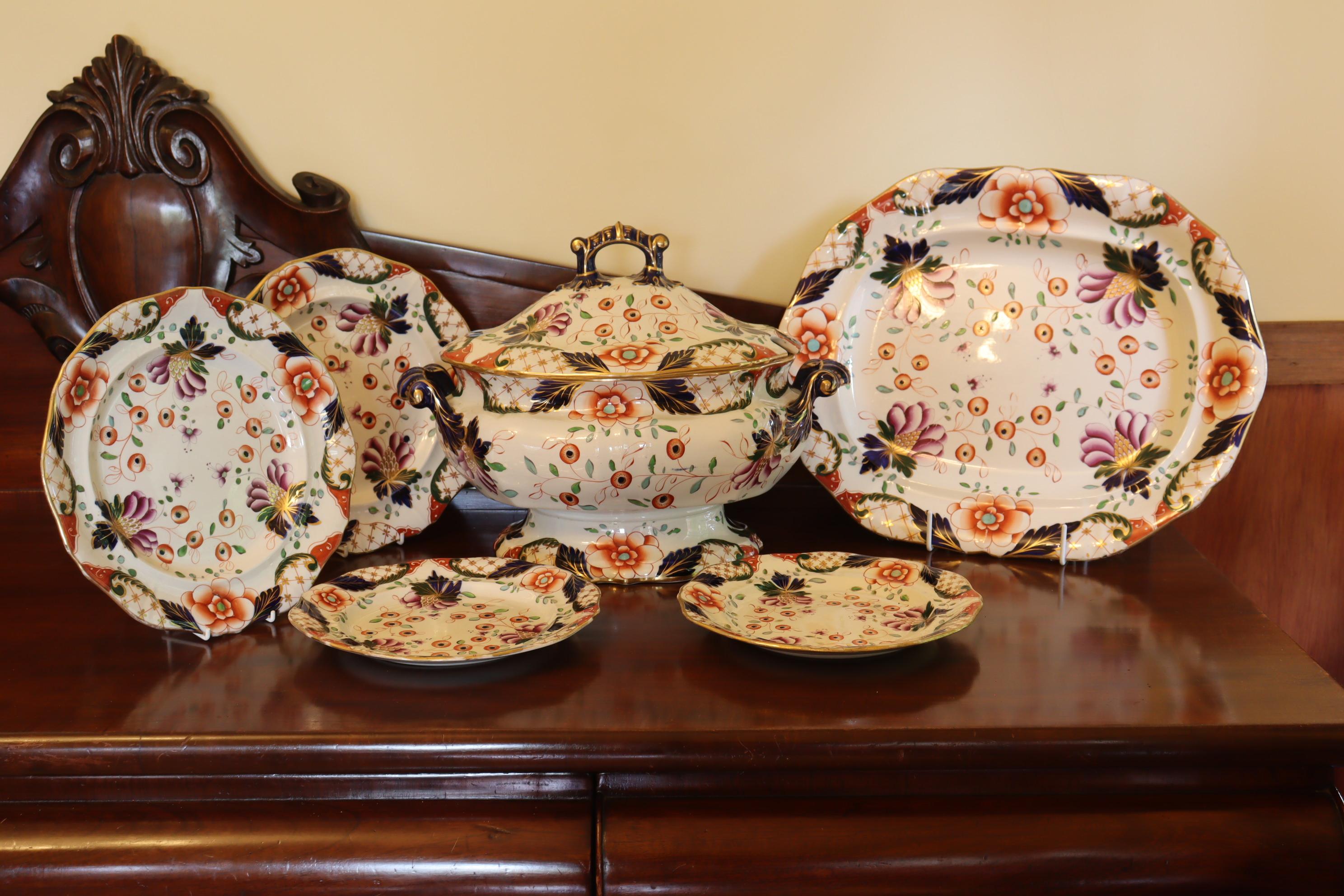 This large and very decorative Stone China lidded soup tureen, platter and four plates are by Davenport and are decorated with a hand painted and gilded pattern using the Imari palette of underglaze blue, iron red and gilding, with the addition of
