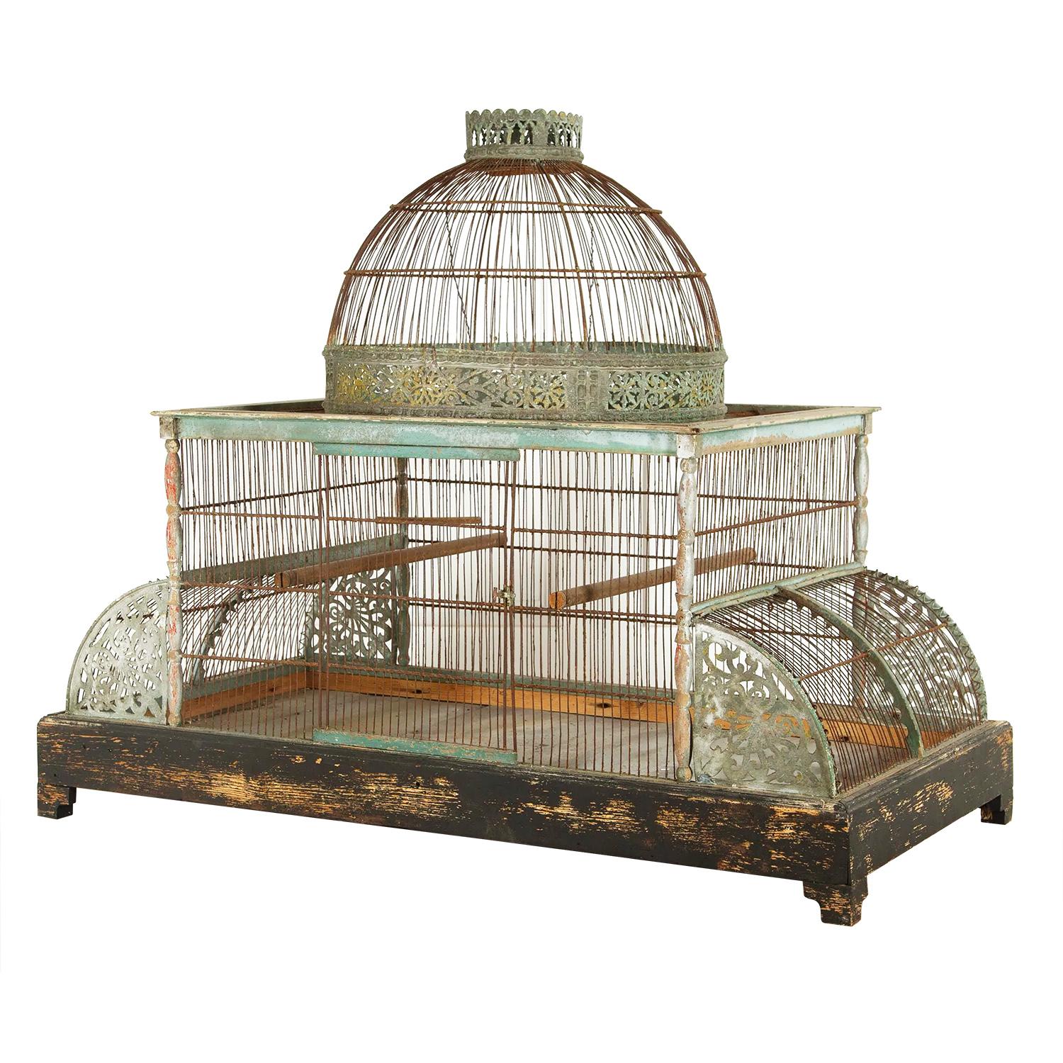Large 19th century bird cage with a wooden base with zinc liner. This piece features curved sides made of pierced metal and hand forged wires with a decorative architectural domed top feature.
 