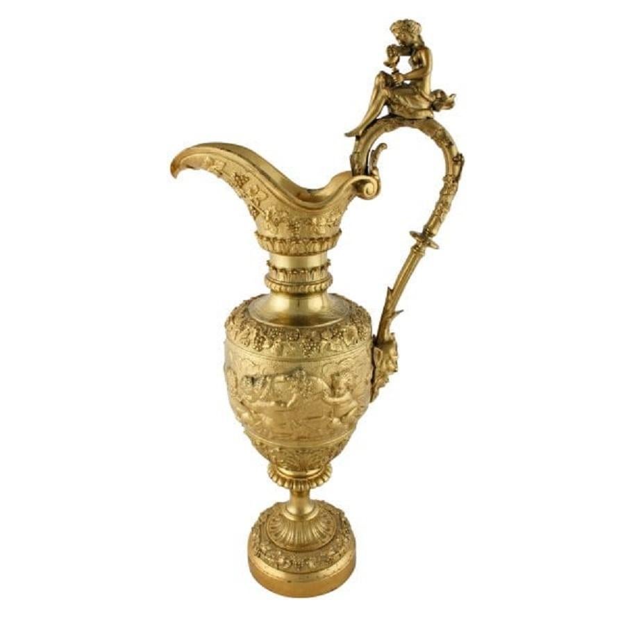 19th century large Ormolu decorative ewer shaped ornament.


The Ewer is decorated with grapes and vines to the handle and the main body has cherubs at study.


The handle top is mounted with a female figure squeezing grapes into a challis and