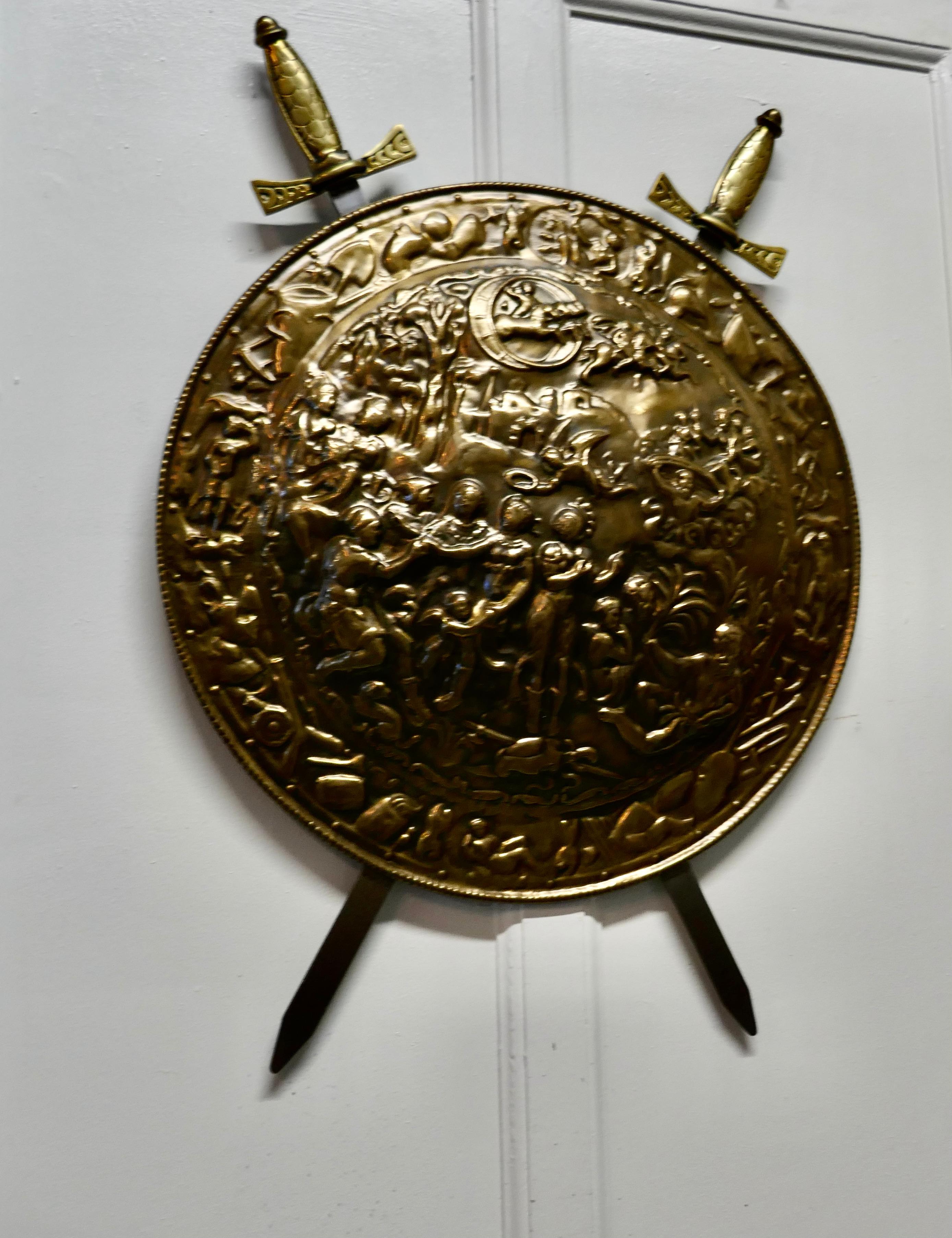 Large decorative wall hanging brass shield with cross swords

A large decorative wall piece the shield is made in hand beaten brass and has scans of mythological characters
The swords are fixed to the back, a good looking piece of traditional pub