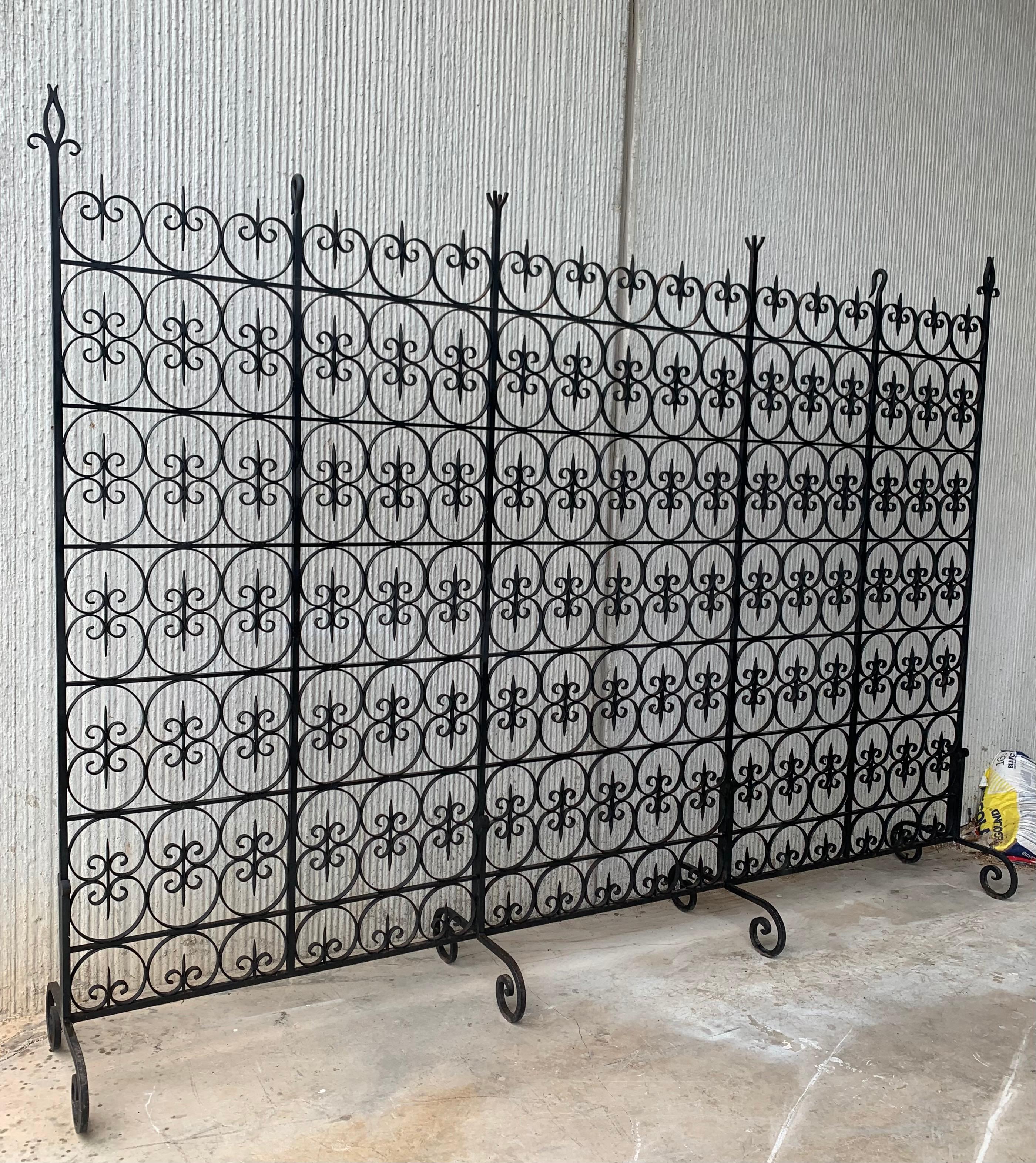 Large decorative wrought iron filigree screen room divider with four legs for a steadiness.