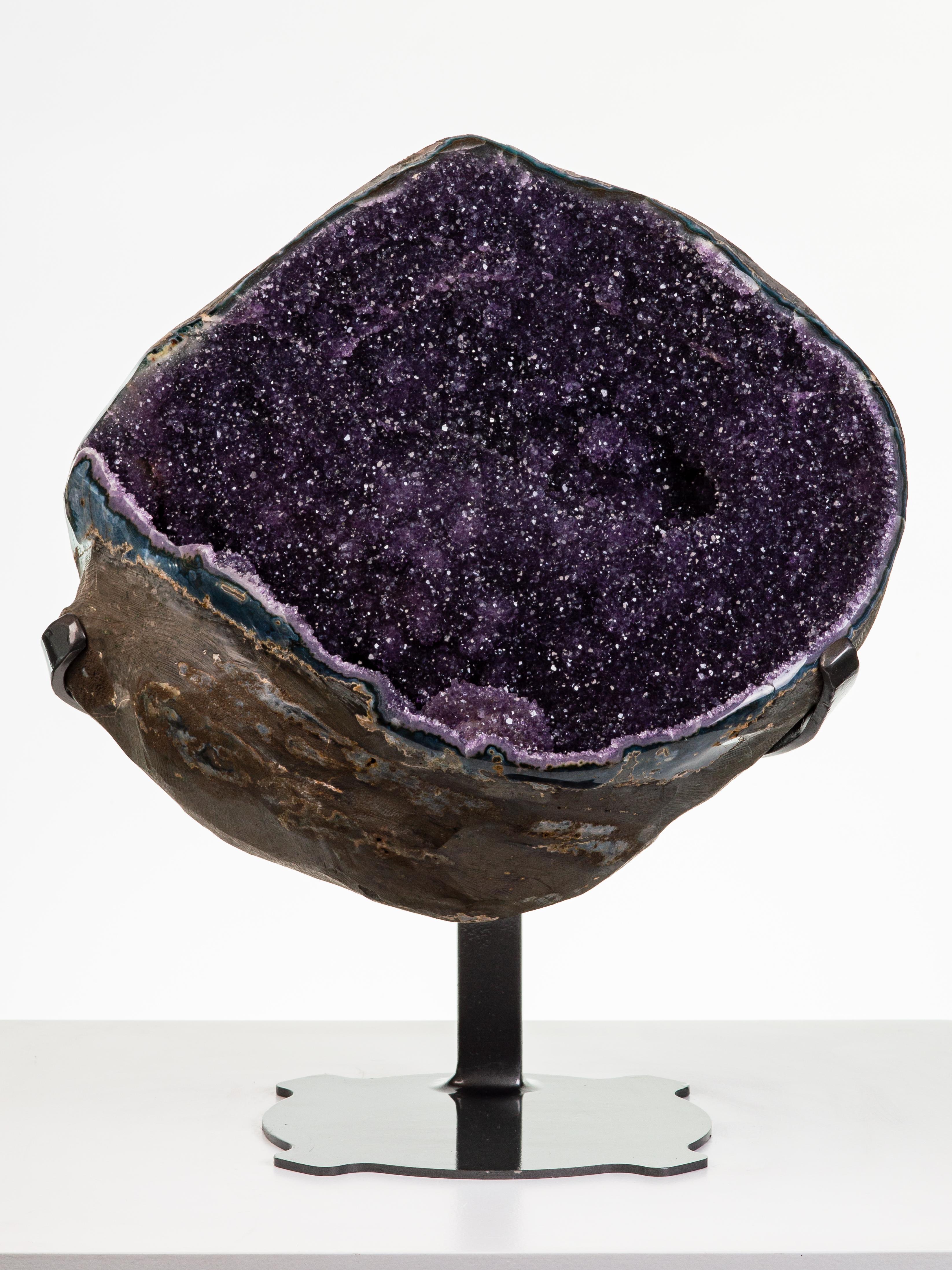 A wonderful and substantial spherical geode is shown here, with deep purple
amethyst crystals enveloping a central calcite. A quintessential geode and a
striking display piece.

This piece was legally and ethically sourced directly in the