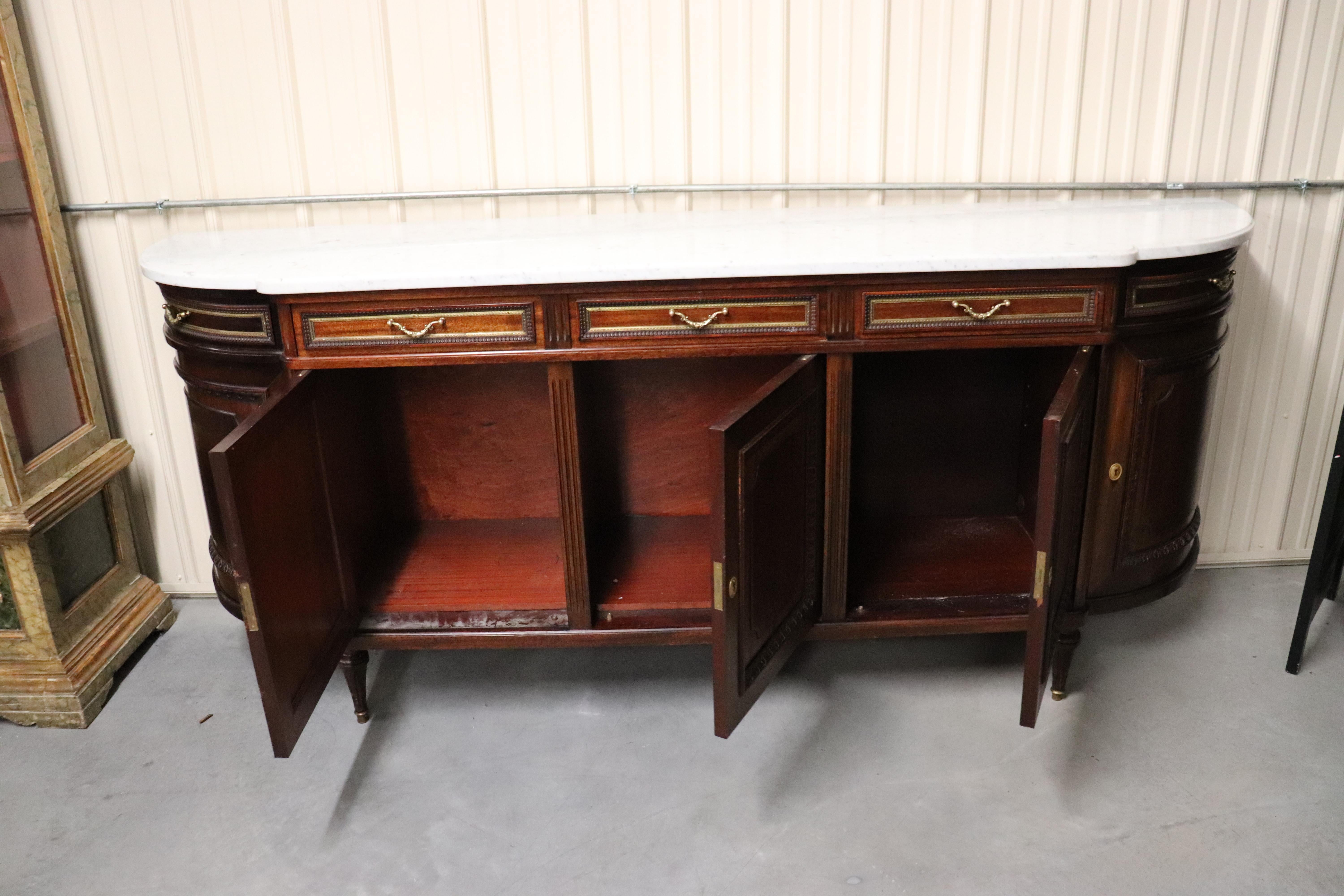 This signed Maison Jansen sideboard is in very good condition and has a beautiful white Carrara marble top. The sideboard dates to the 1940s and is French and measures 99 wide x 41 tall x 24 deep.