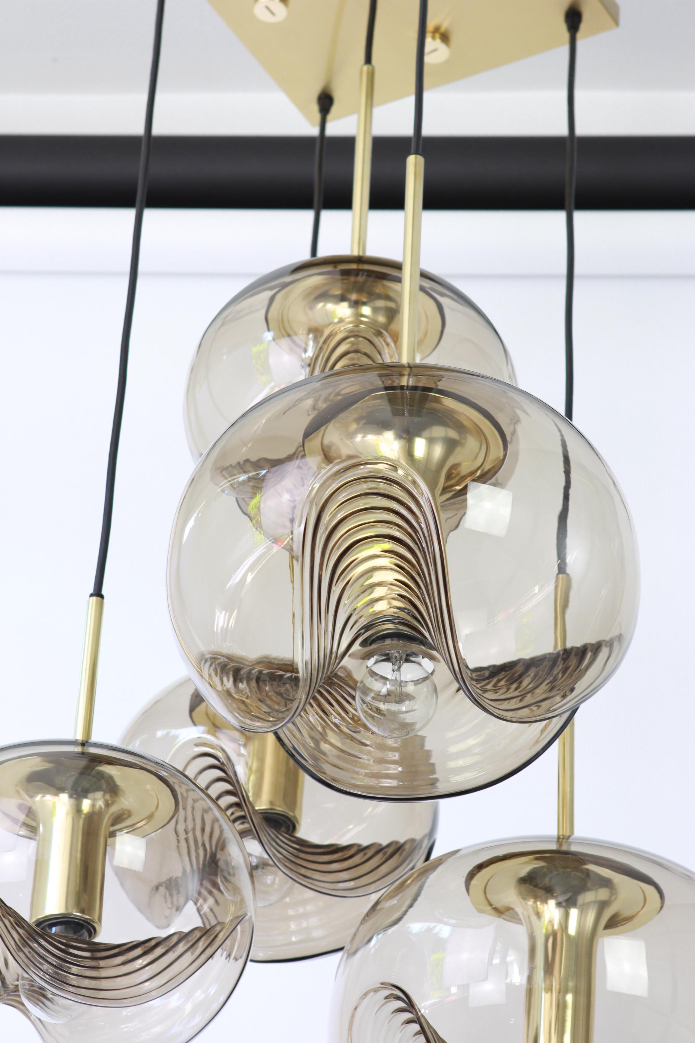 Un grand lustre spécial en cascade conçu par Koch & Lowy pour Peill & Putzler, fabriqué en Allemagne, vers les années 1970, avec 5 verres ronds fumés Biomorphic.
Merveilleuse forme de vague et effet de lumière stupéfiant.
Douilles : 5 x E26 /E27