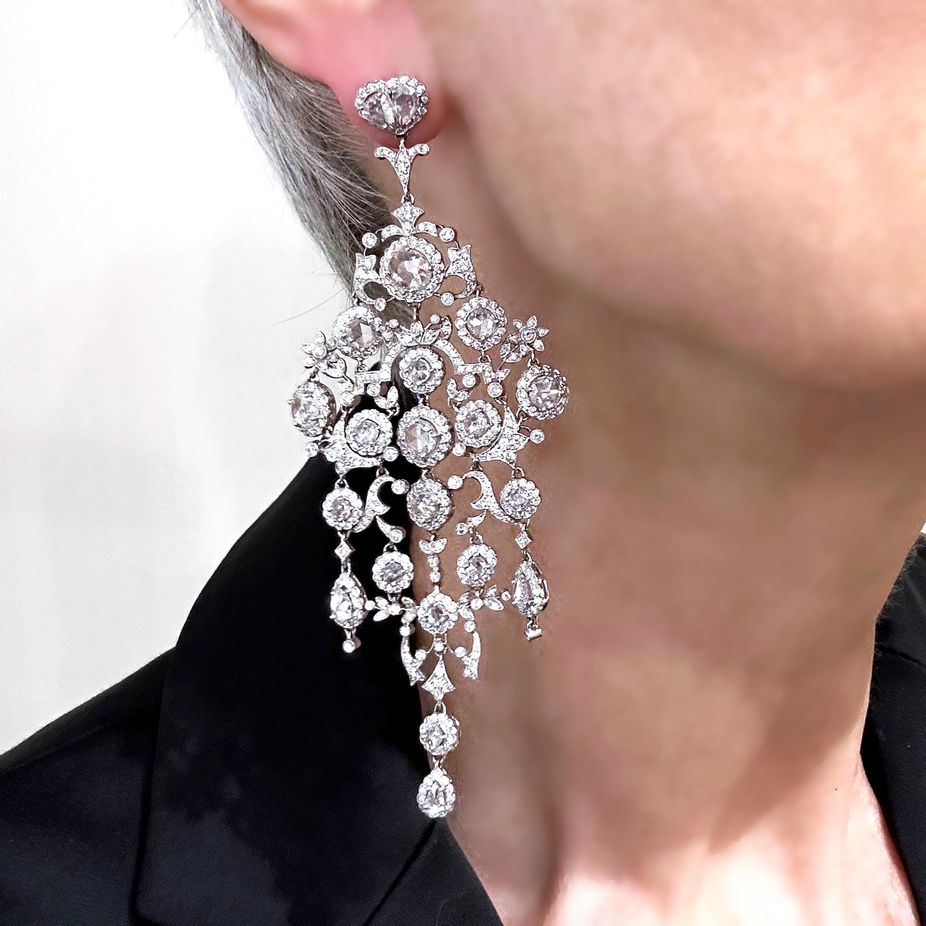 A pair of large chandelier diamond earrings, with clusters of rose-cut diamonds, surrounded by round brilliant-cut diamonds, on an articulating, diamond pave set, openwork frame of scrolls and flowers, with an approximate total diamond weight of