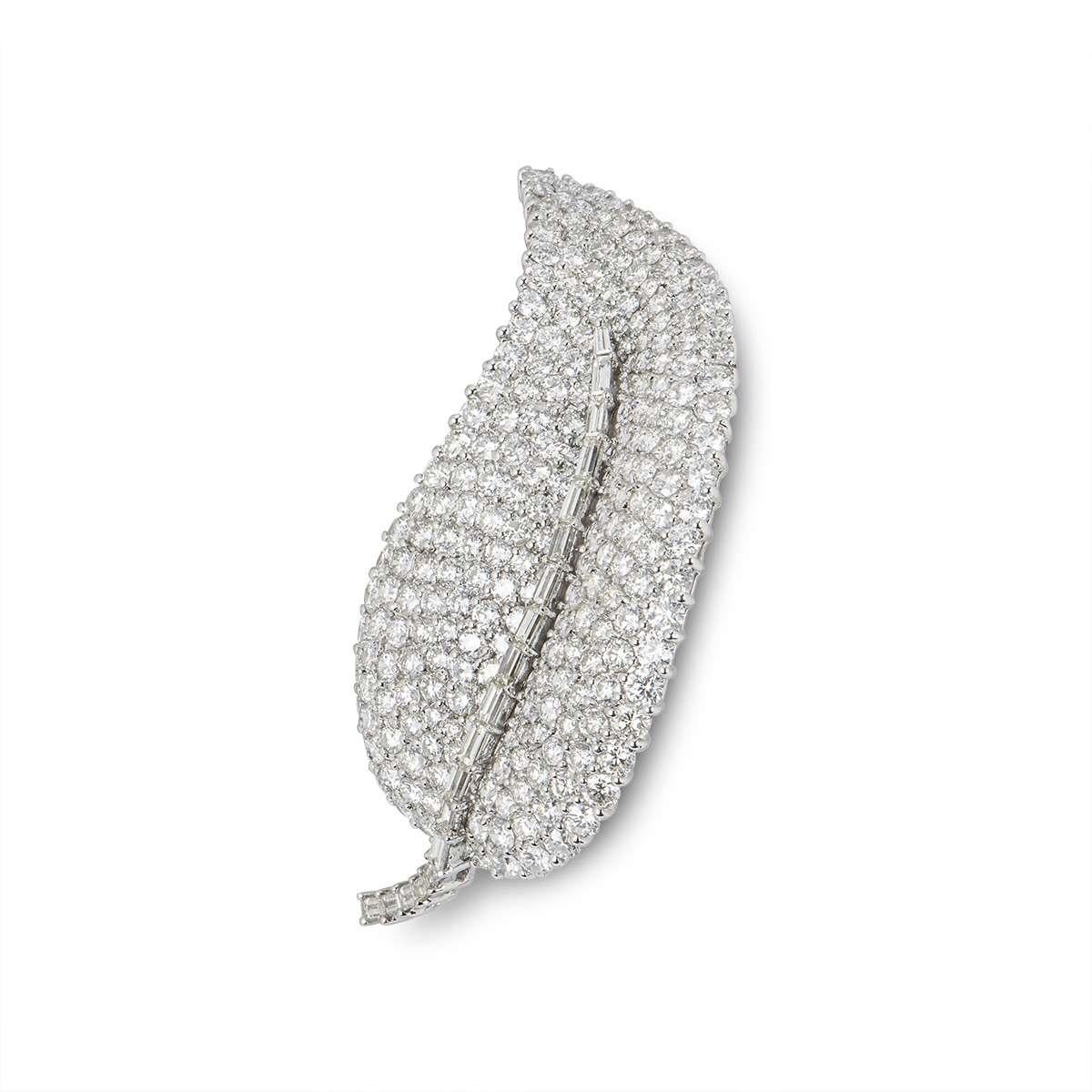 An 18k white gold diamond set leaf brooch. The body of the brooch is composed of round brilliant cut diamonds, each individually claw set, accentuated by the stem composed of claw set baguette cut diamonds. The diamonds total approximately