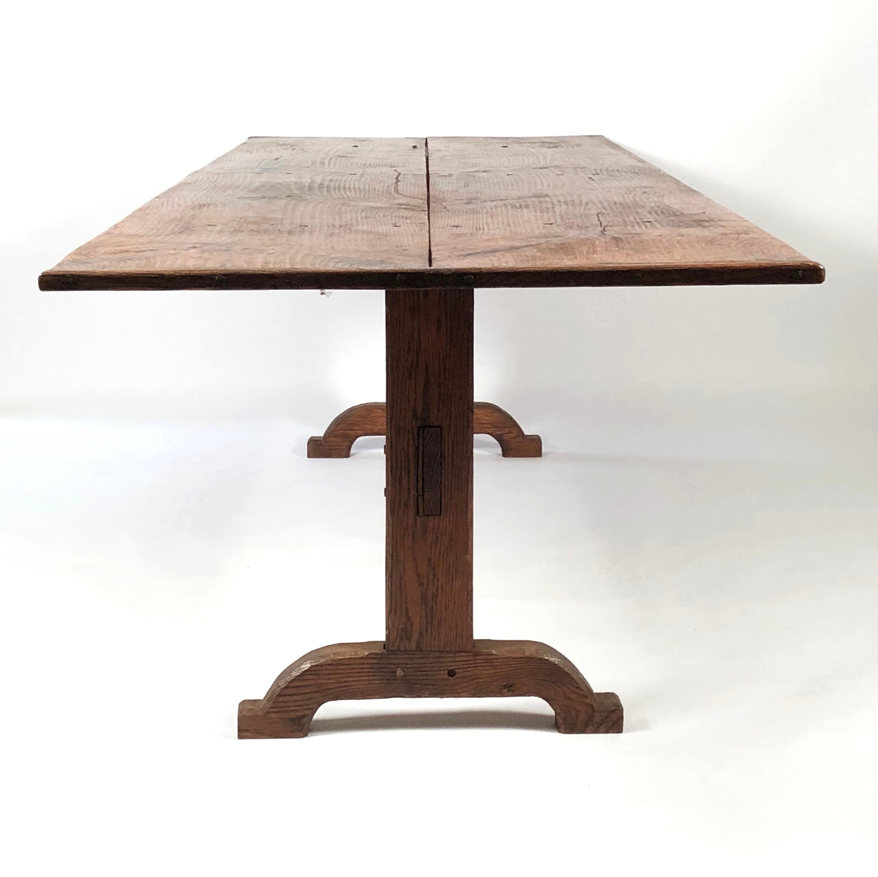 A large country farm dining table, the pine top comprised of two boards with traditional breadboard ends, supported by two oak trestle supports joined by a cross stretcher. Great proportions, with room for at least 10-12, with plenty of legroom.