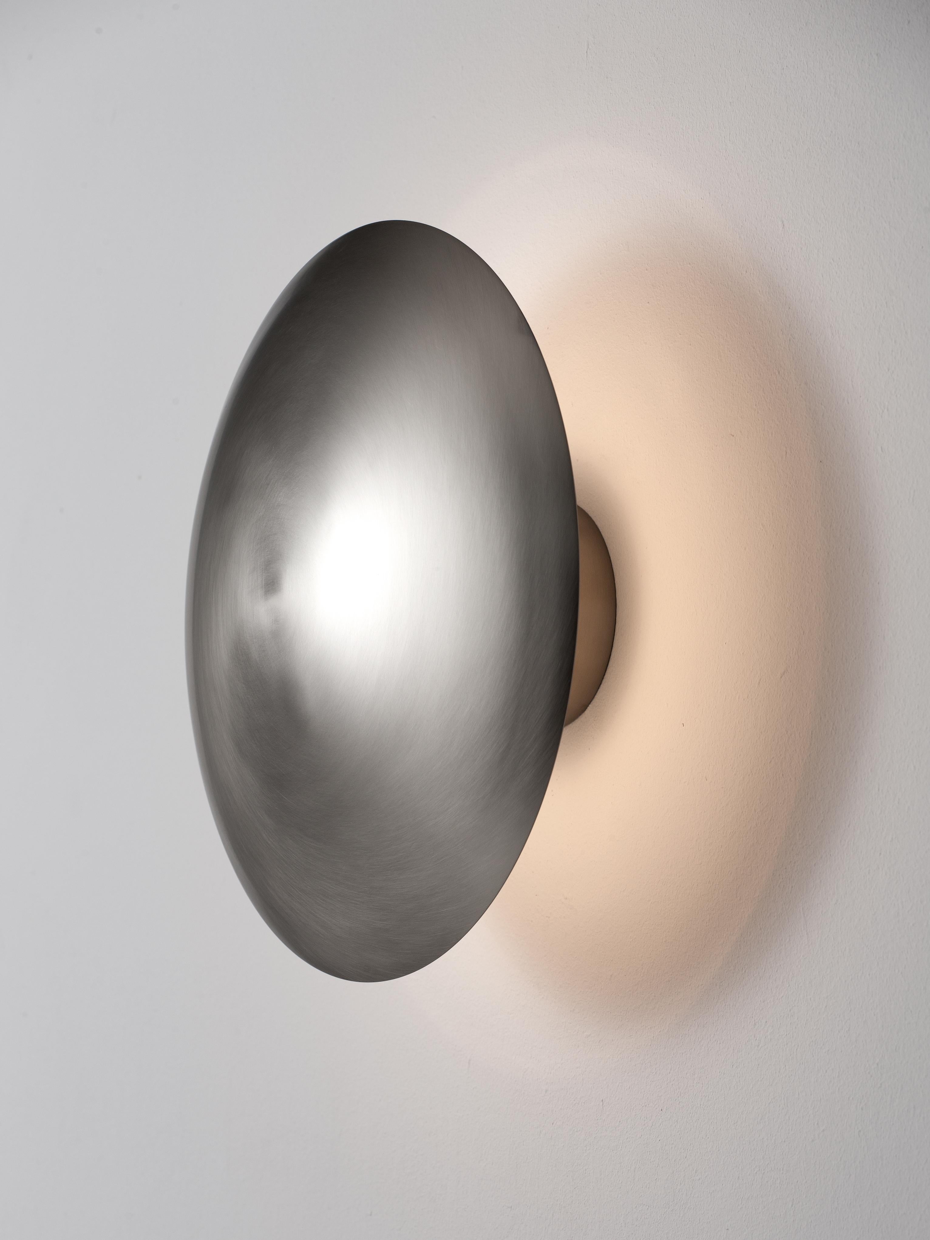 Large Disco wall lamp by Jordi Miralbell, Mariona Raventós
Dimensions: D 35 x W 14.5 x H 35 cm
Materials: Metal.
Available in 2 sizes: D24, D35 cm.

This metallic disc, available in two sizes, M and L, reflects its light on the wall, creating a halo