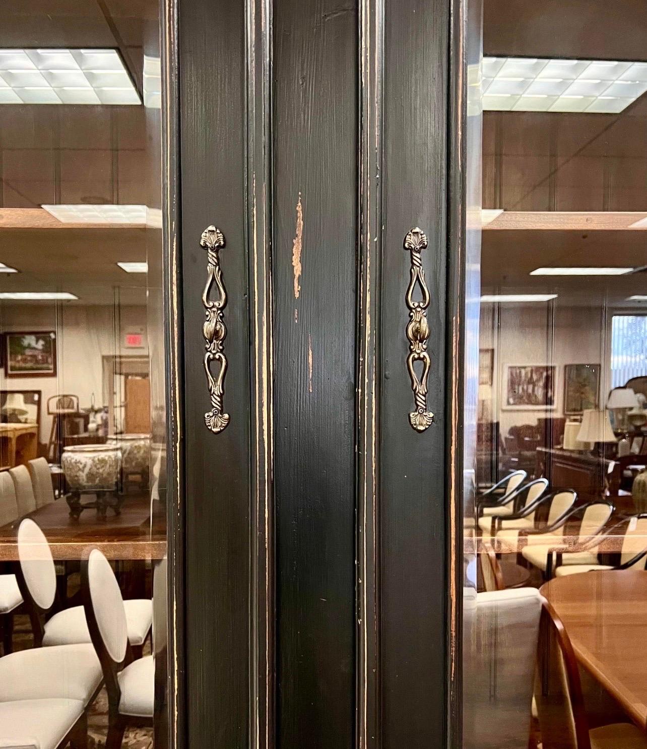 Large painted china cabinet in a distressed black finish and consisting of two parts, a top and a bottom for ease of movement.  The top has two front doors that open to shelves.  The bottom has two dovetailed drawers above two doors that open to