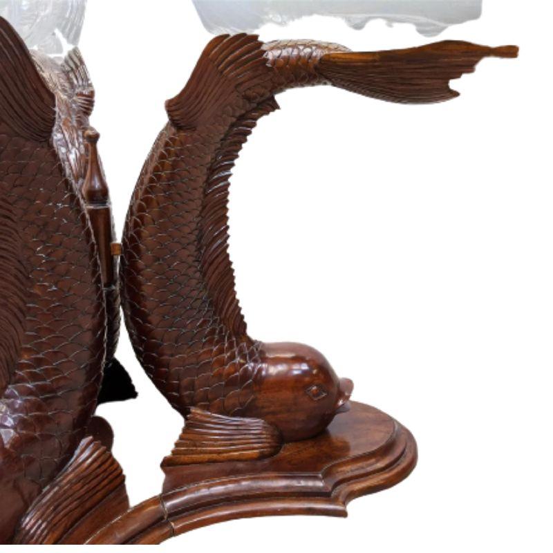 A carved wood dolphin base center pedestal table with three carved dolphins, their heads at the base and their tails acting as support for the round glass top.  Intricate carved details make this table very special 