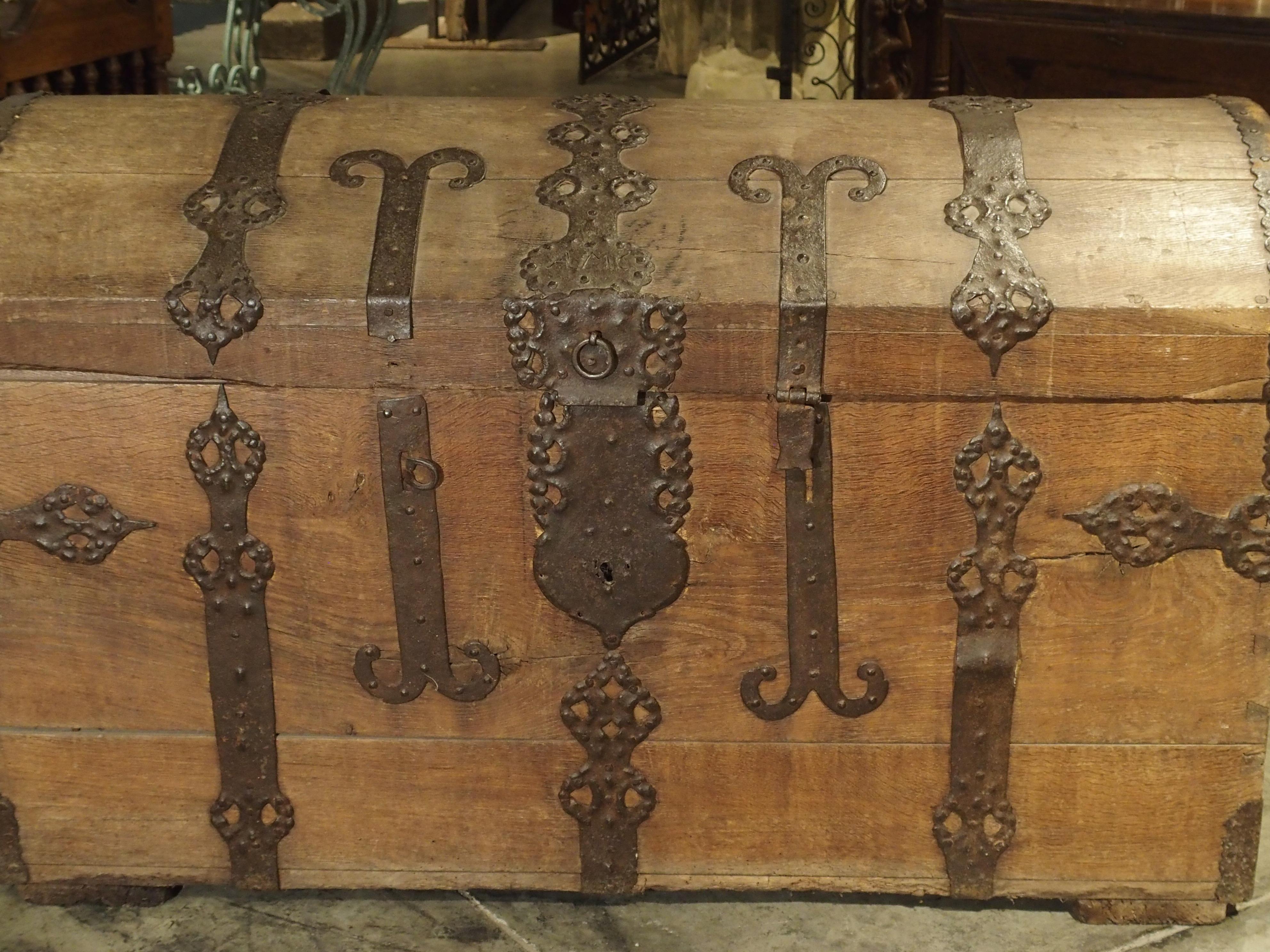 This large French oak and iron trunk is typical of those coming from Alsace, France. It dates to the late 18th century and has impressive reticulated strapwork and motifs throughout. On either side of the top cover are conforming iron ornamentation