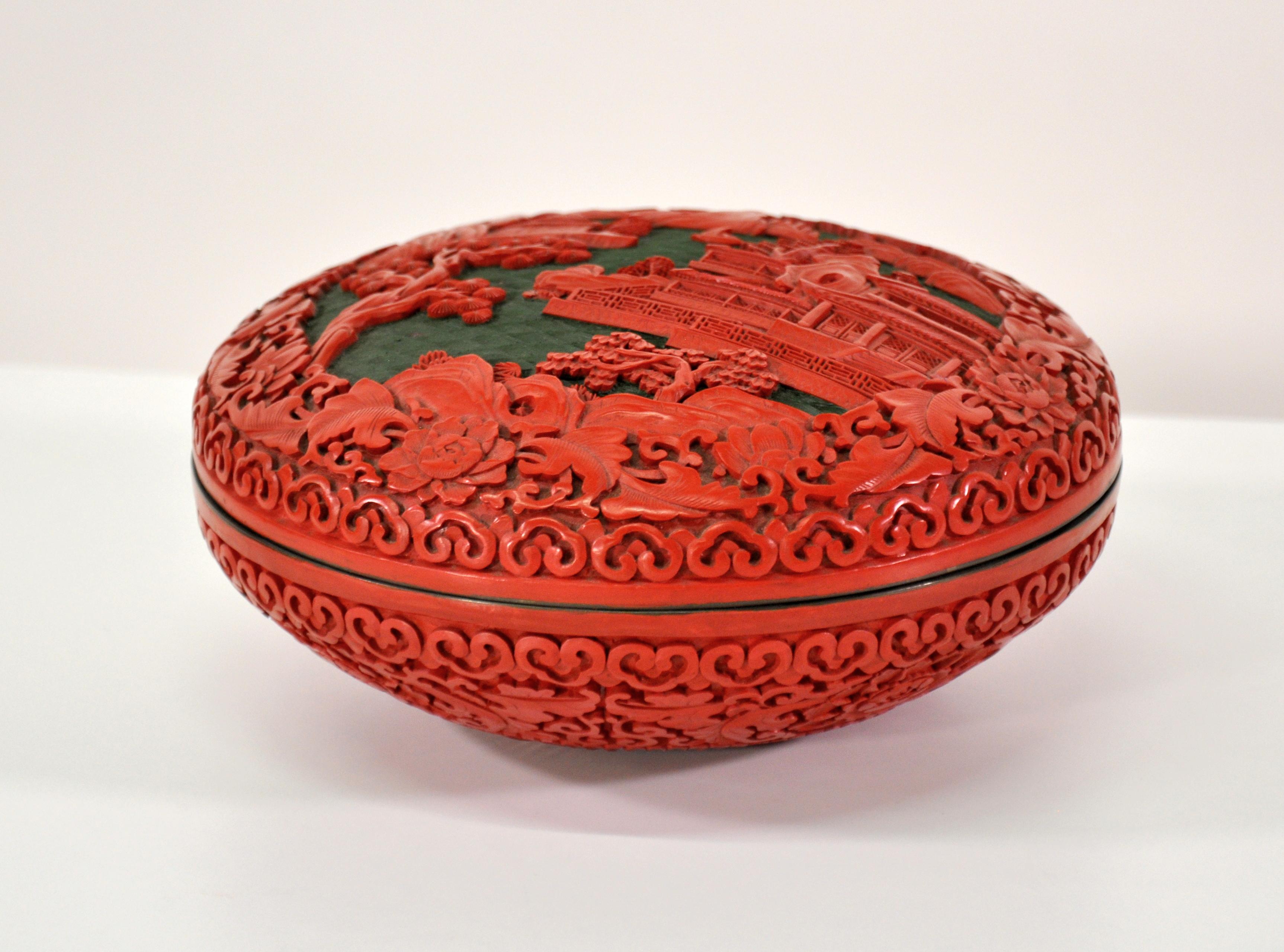 A large vintage Chinese red cinnabar box with deep relief carved lid depicting peonies, trees and a landscape with a palace. The round box has a domed lid and a black lacquer interior with brass rim.
In Chinese culture, the peony represents