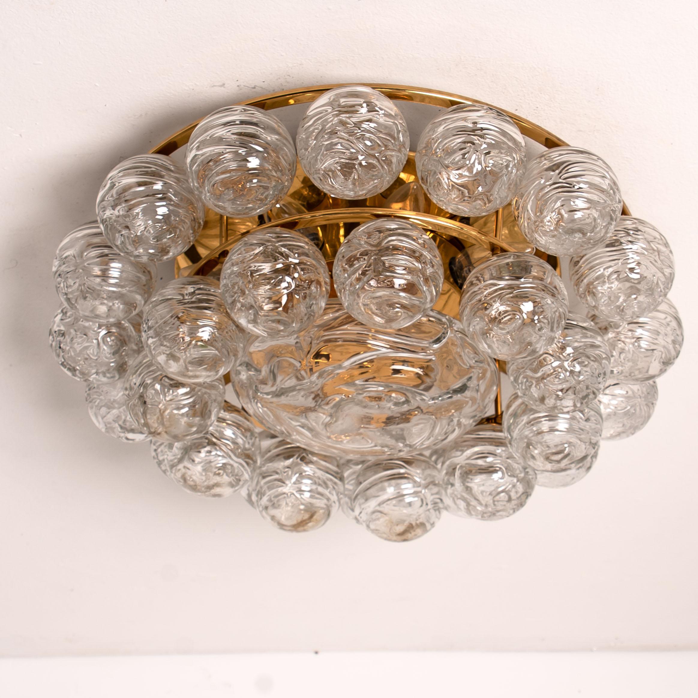 A flushmount light fixture by Doria Leuchten, Germany, manufactured in midcentury, circa 1960.
The lamp is made of a nickeled backplate and a brass frame which holds 27 hand blown glass balls and one glass disc in the centre. Illuminates