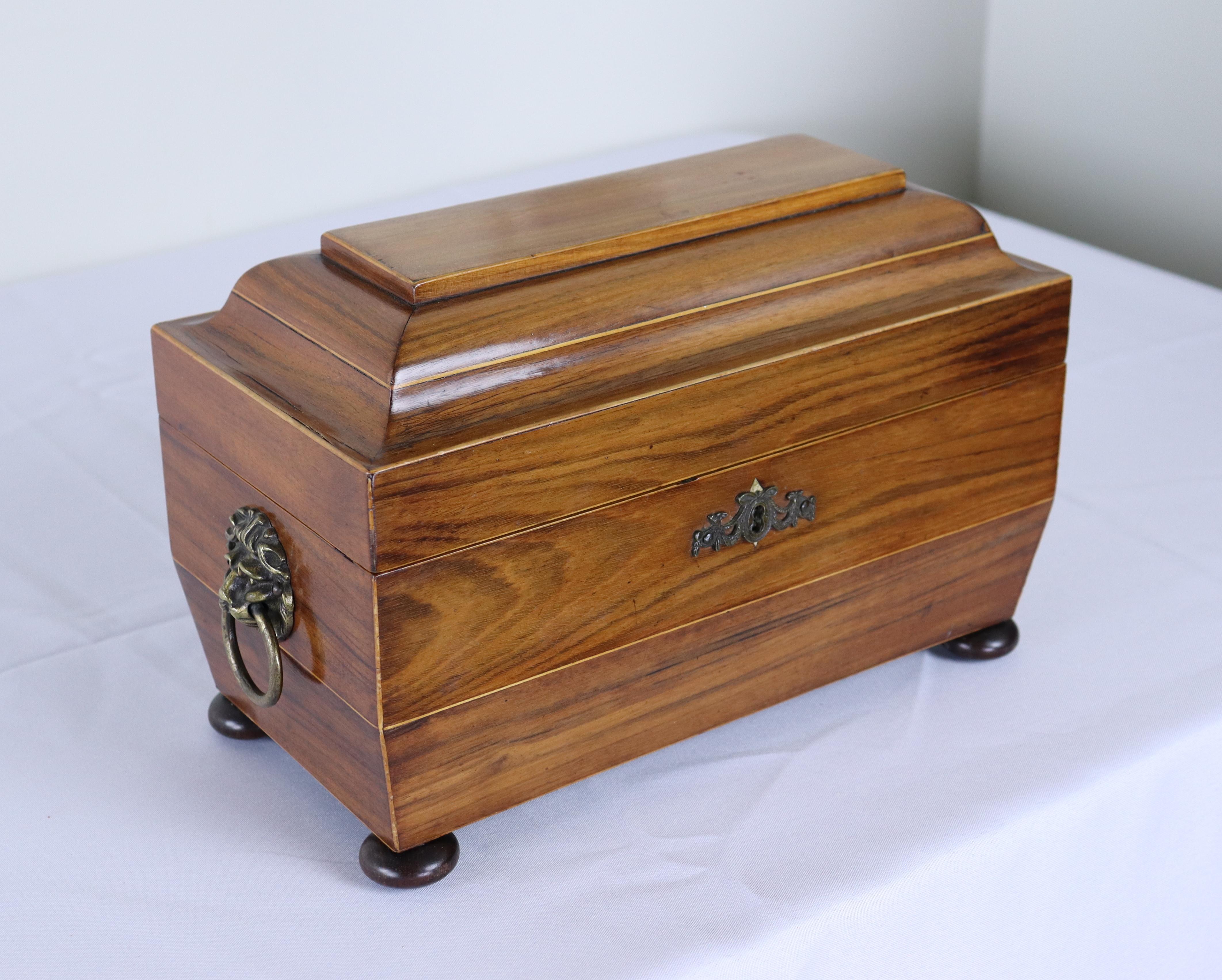 An early double tea caddy with satinwood inlay around the top and brass lions head handles on either side.  The two interior tea compartments and the glass insert are all in good antique condition.  The mahogany has wonderful shine and patina, and