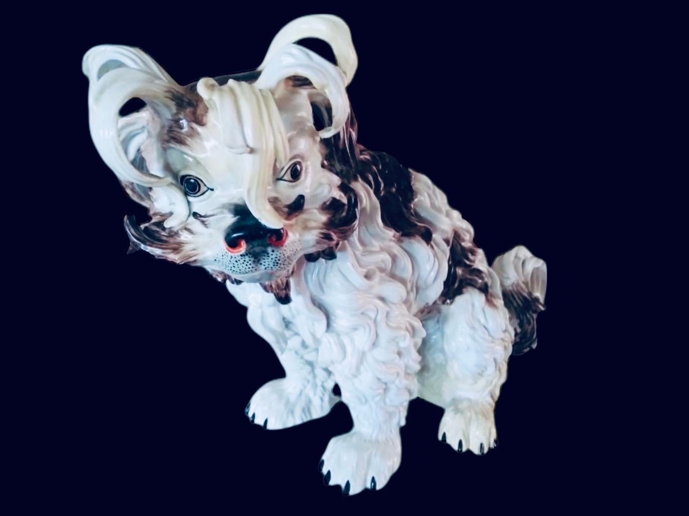 Se trata de una escultura de perro de Dresden Porcelain. Representa a un perro peludo boloñés de tamaño natural. Tiene el pelo rizado, gris y blanco, y grandes ojos negros. Lleva el sello de Dresde.