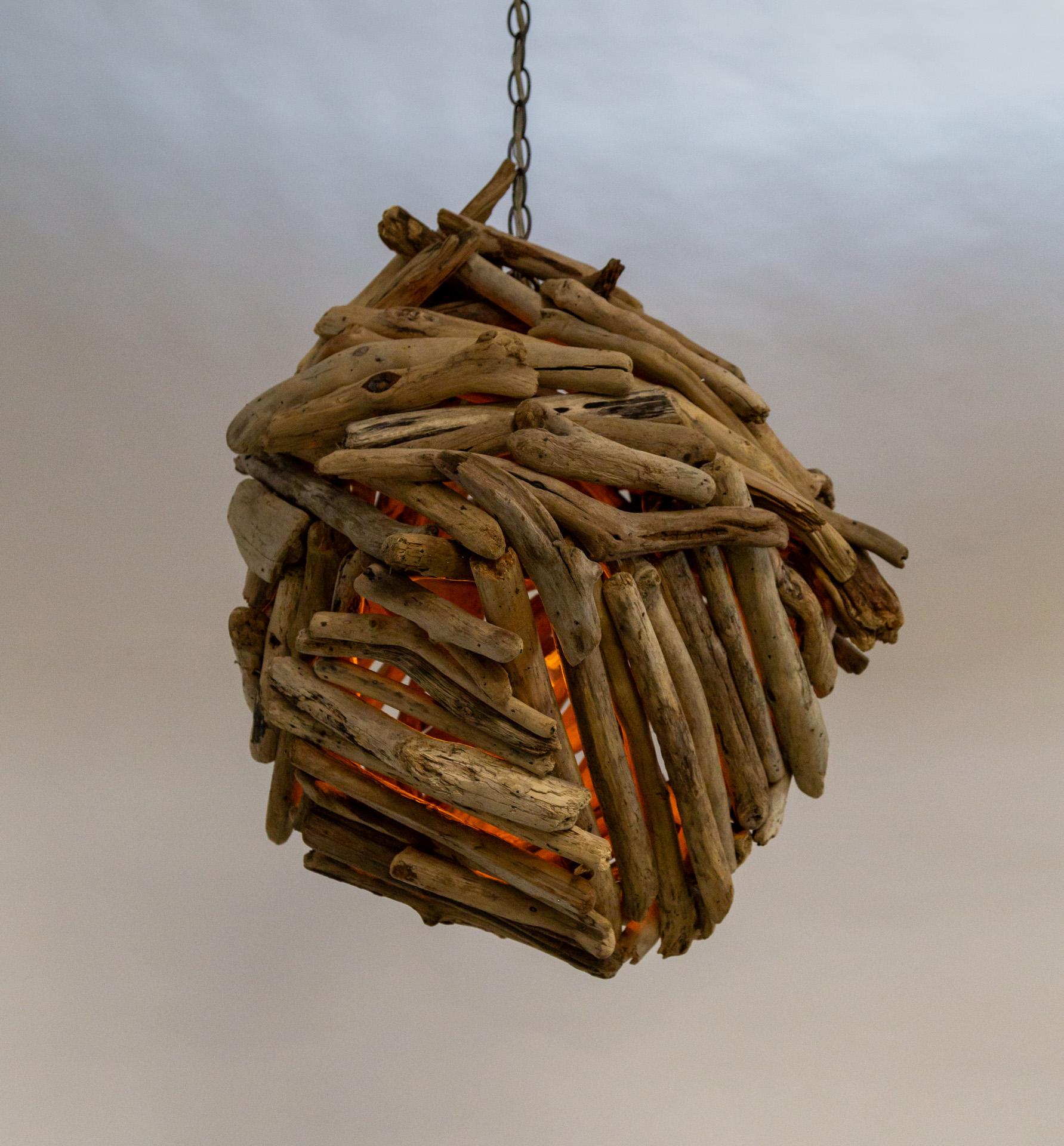 A large, one-of-a-kind pendant light comprised of pieces of driftwood meticulously placed into a bundle.  It has two medium base sockets suspended inside that can be accessed by a subtle break in the cluster on top.  Light can be seen from between