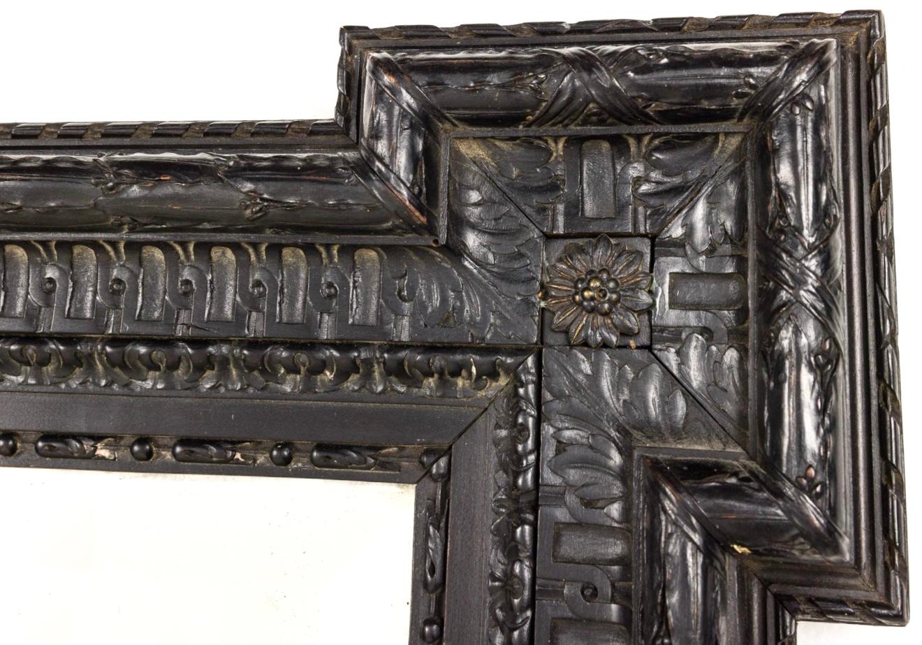 Large scale 19th century Dutch Ebonized Wall Mirror. Mirror features a striking ebonized finish, giving it a rich sophisticated appearance. Frame has intricate decorative details including floral accents in each corner. In the 19th century these