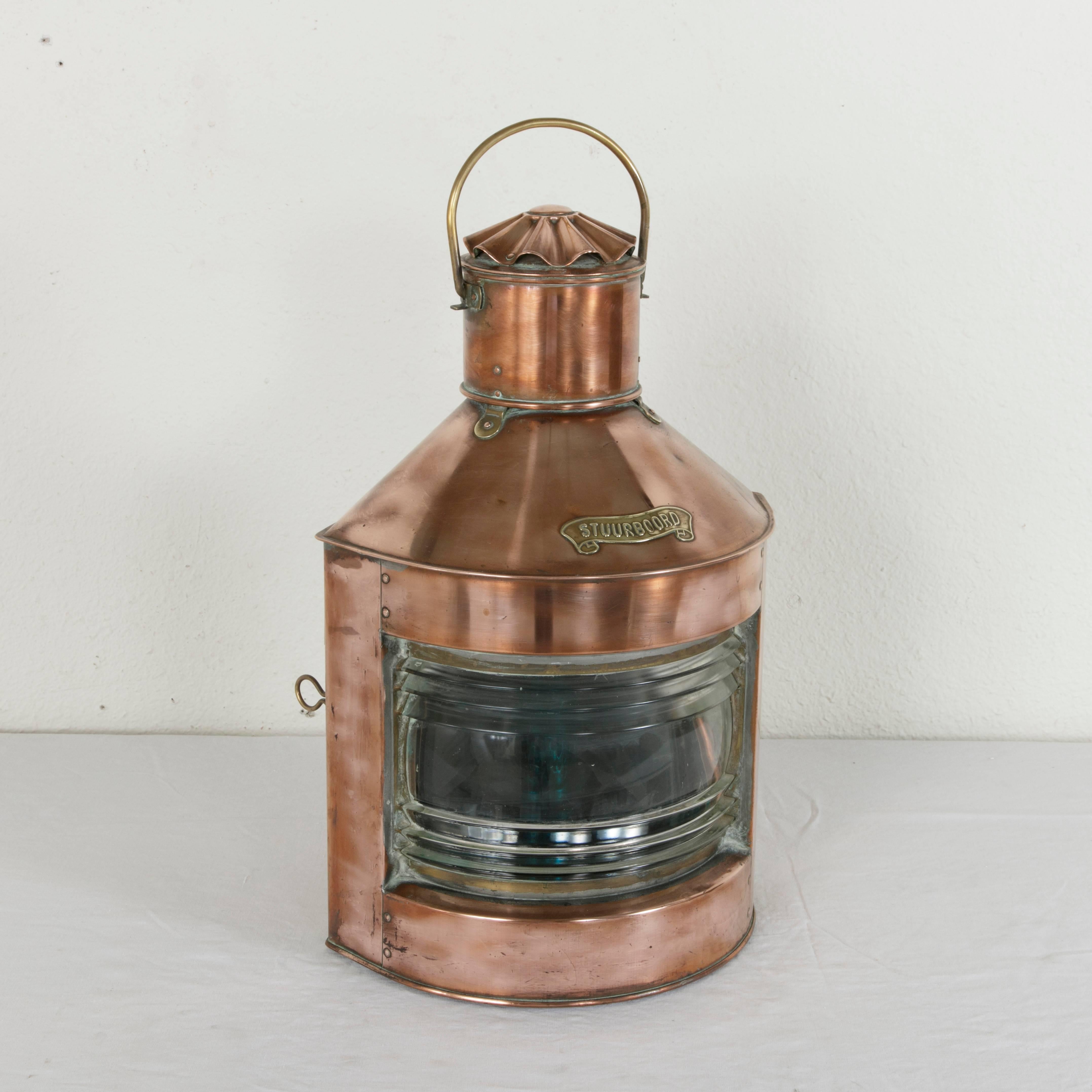 This large circa 1900 Dutch copper nautical lantern features a brass label in the form of a scroll marked Stuurboord or starboard in Dutch. A latch at the back allows it to be opened and reveals an interior with the original glass hurricane lamp and