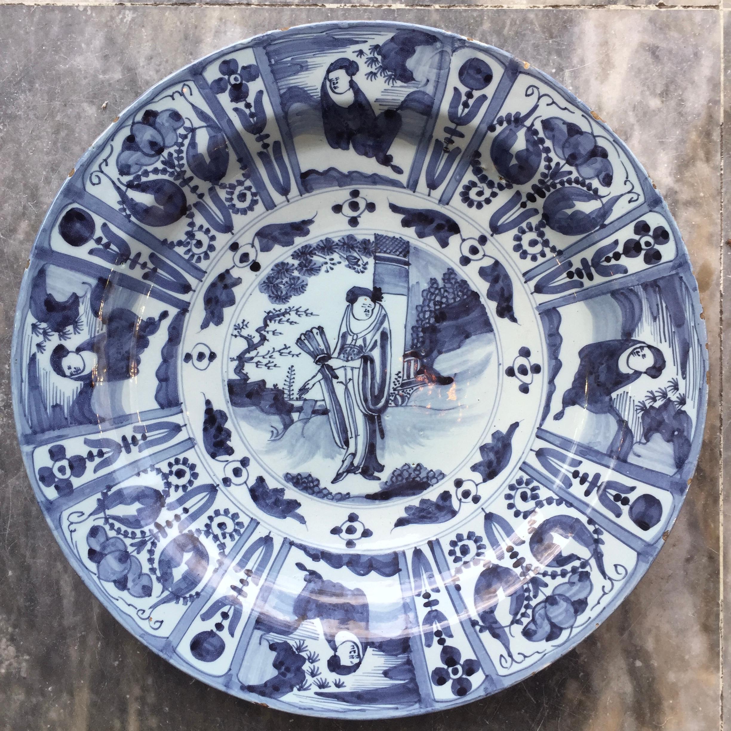 Ville : Delft
Atelier : Inconnu
Date : Dernier quart du XVIIe siècle

Grande assiette bleue et blanche de style Whiting / Tianqi
Décorée de Long Eliza au centre, entourée de huit cartouches avec des fleurs et des personnages.
Copie exacte des