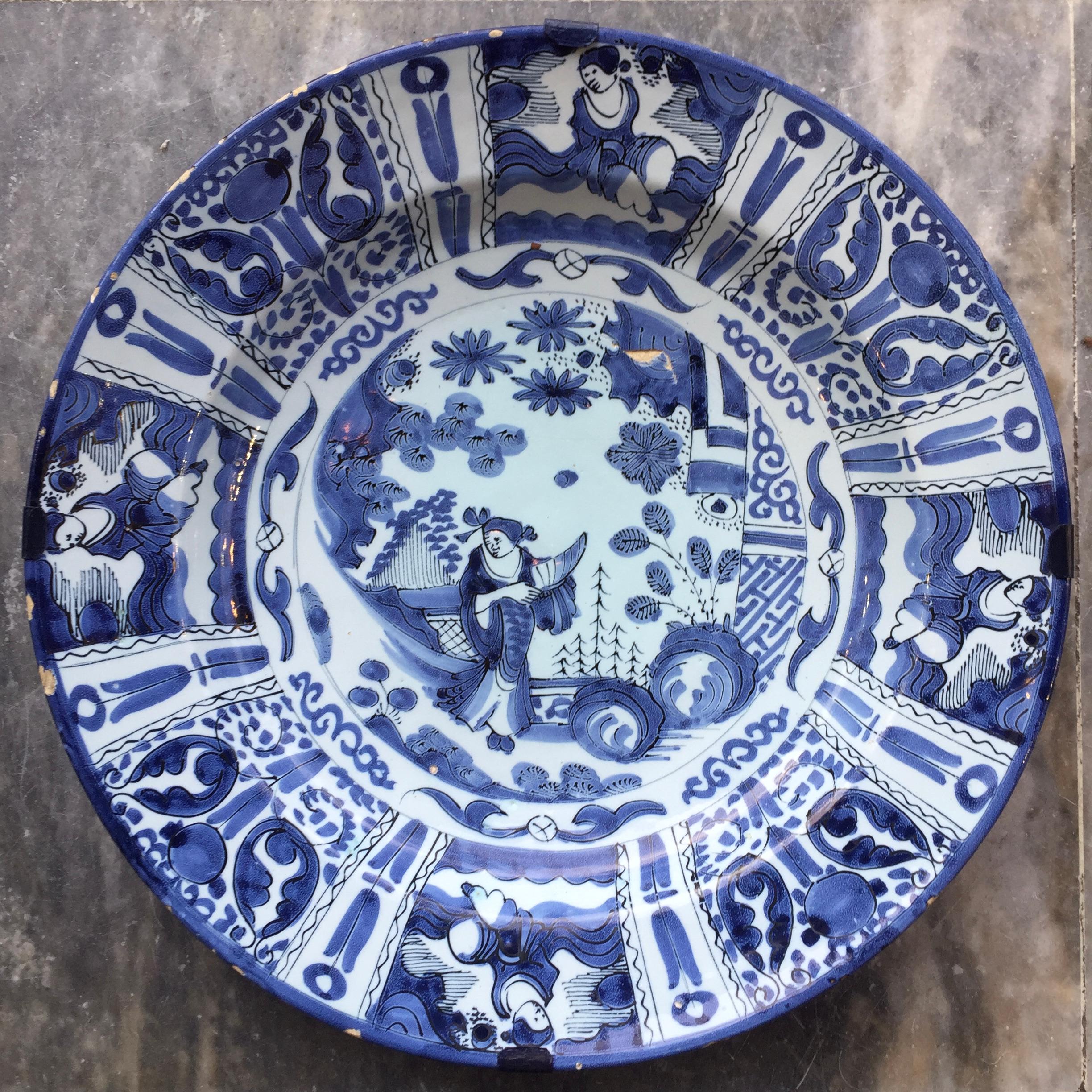 City: Delft
Workshop: Unknown
Date: Last quarter of the 17th century

A large blue and white plate in Wanli / Tianqi style
Decorated with a Chinese figure in the center surrounded by eight cartouches with flowers and figures.
Exact copy of the