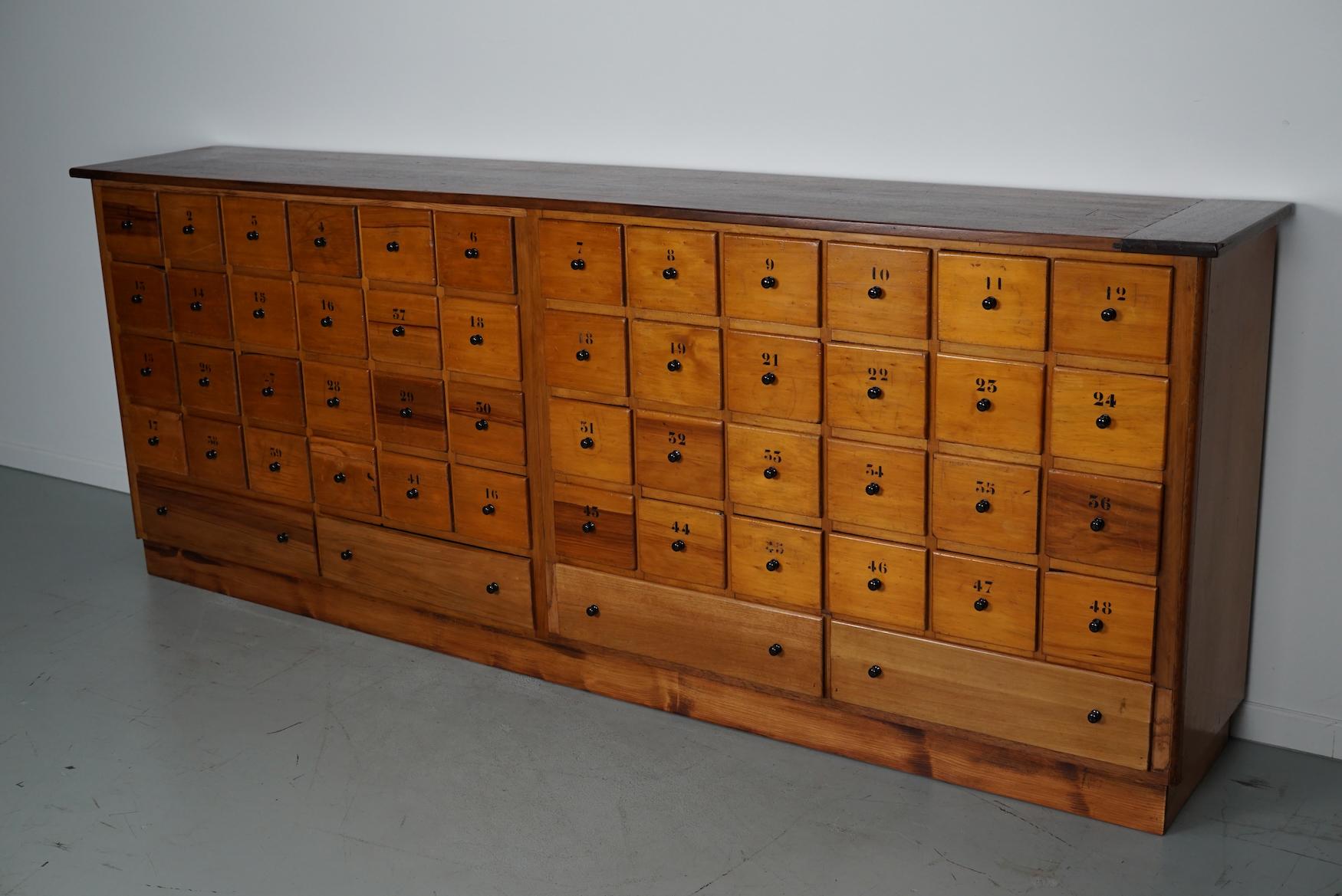 This apothecary bank of drawers was designed and made circa 1950 in the Netherlands. It was made from beech and it features 52 drawers with black metal knobs and numbers. The interior dimensions of the drawers are: DWH 33 x 14.5 and 52 x 13 cm.