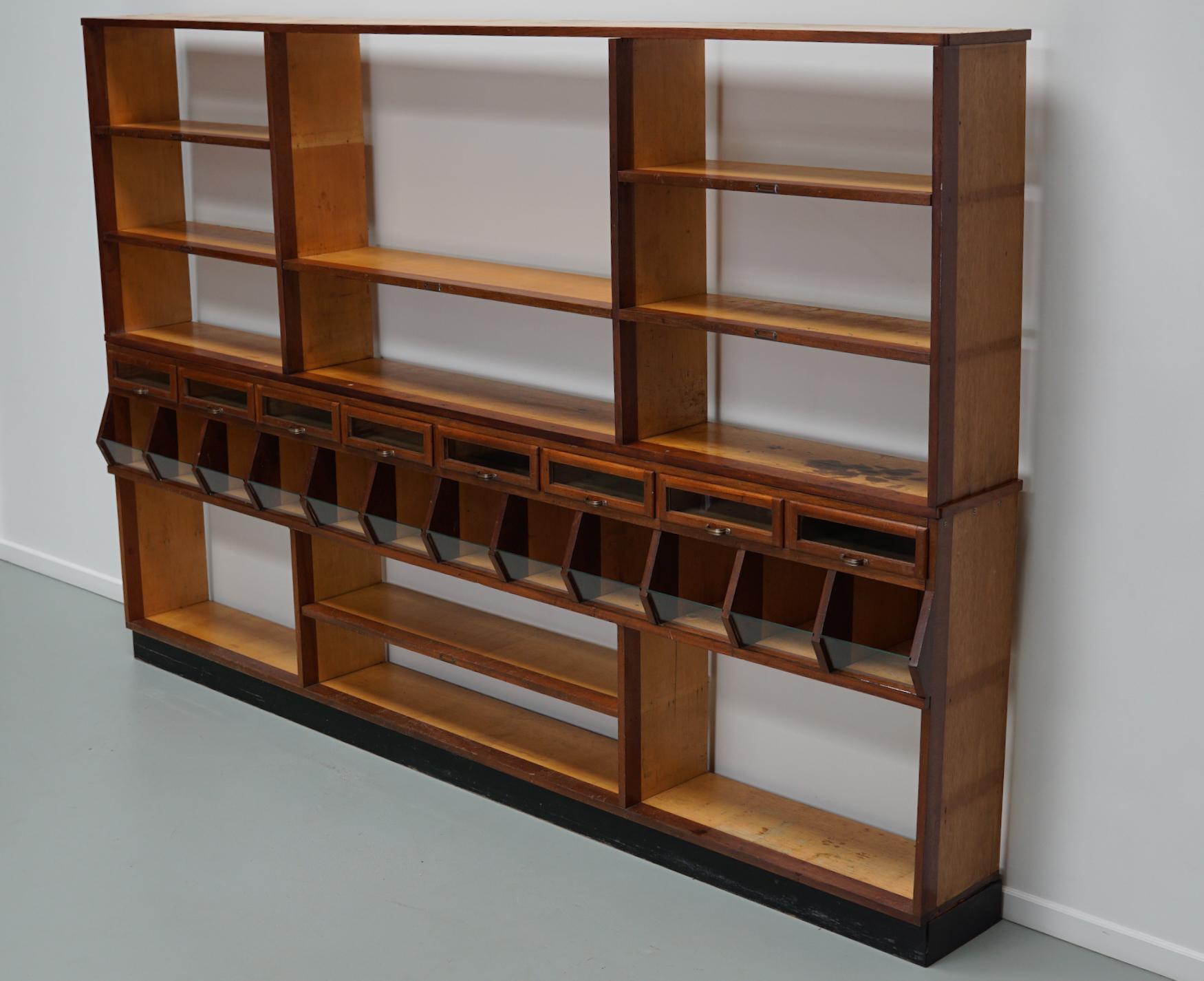 Cette armoire de magasin a été fabriquée dans les années 1950 aux Pays-Bas. Cette pièce comporte 12 compartiments et 8 tiroirs avec façades en verre et 6 étagères. Il a été utilisé à l'origine dans une épicerie au milieu du XXe siècle dans la ville