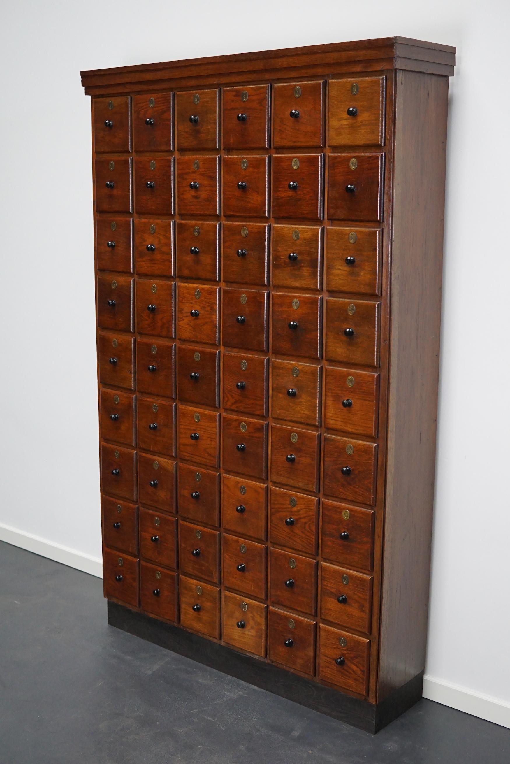 This apothecary cabinet was made circa 1920s in the Netherlands. It features 54 drawers with amazing bakelite knobs and brass numbers. It was originally made for a barber in the Amsterdam region. It was used to store individual shaving supplies of