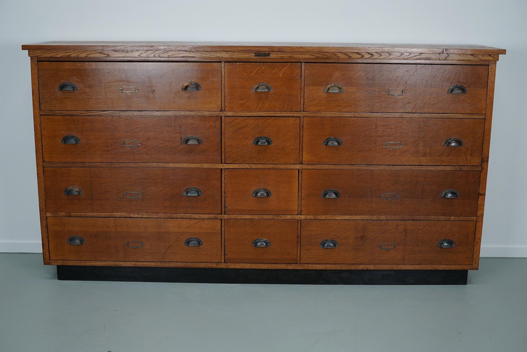 This apothecary cabinet was made circa 1930s in the Netherlands by the company Nefkens in Breda. It features 12 drawers in two different sizes with nice brass handles. It is made from oak / oak veneer and it remains in a very good condition. The