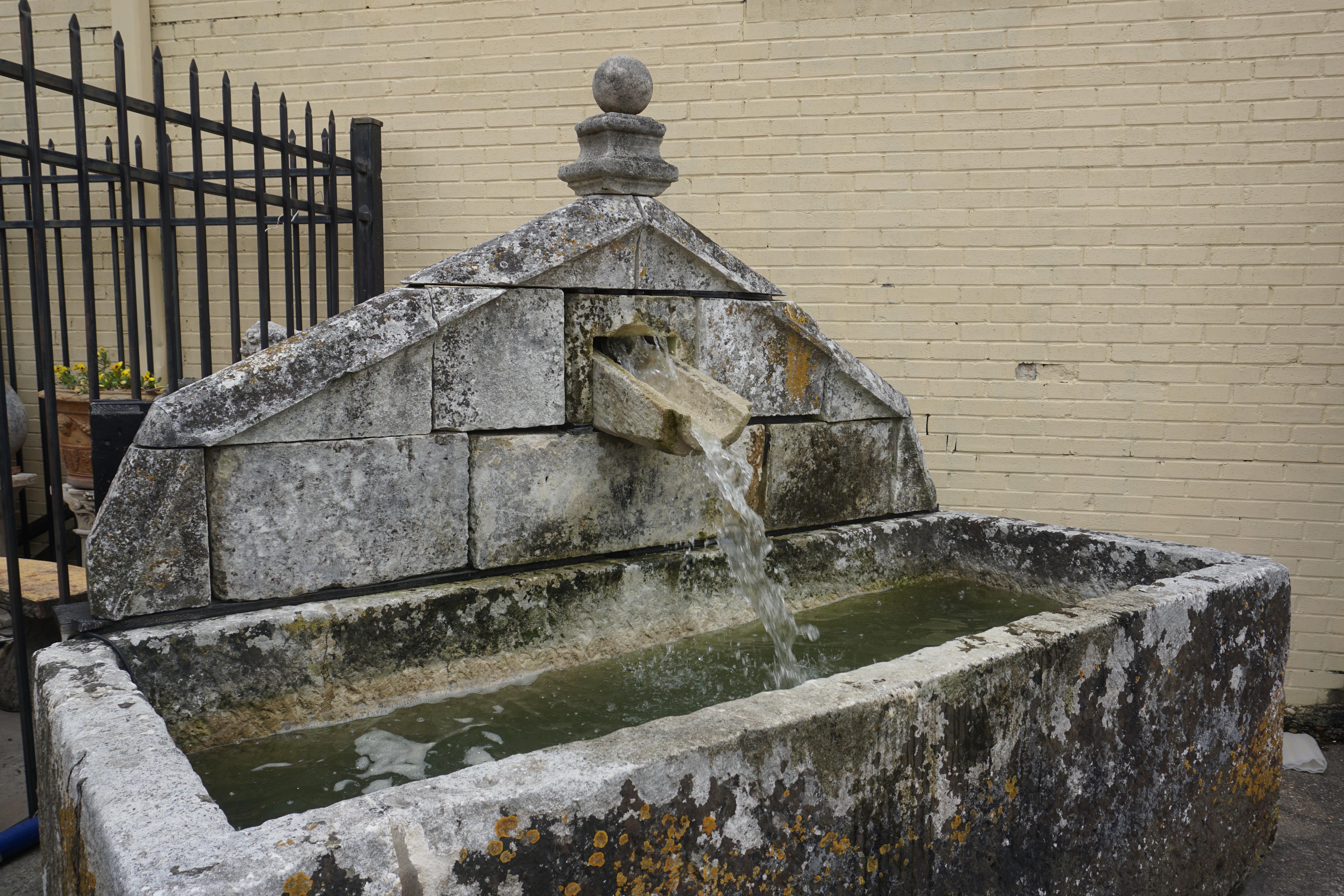 Large antique French limestone watering fountain. The triangular shaped fountain wall consists of original and re purposed carved limestone blocks. Holds in excess of 300 gallons.

Measurements: 
103