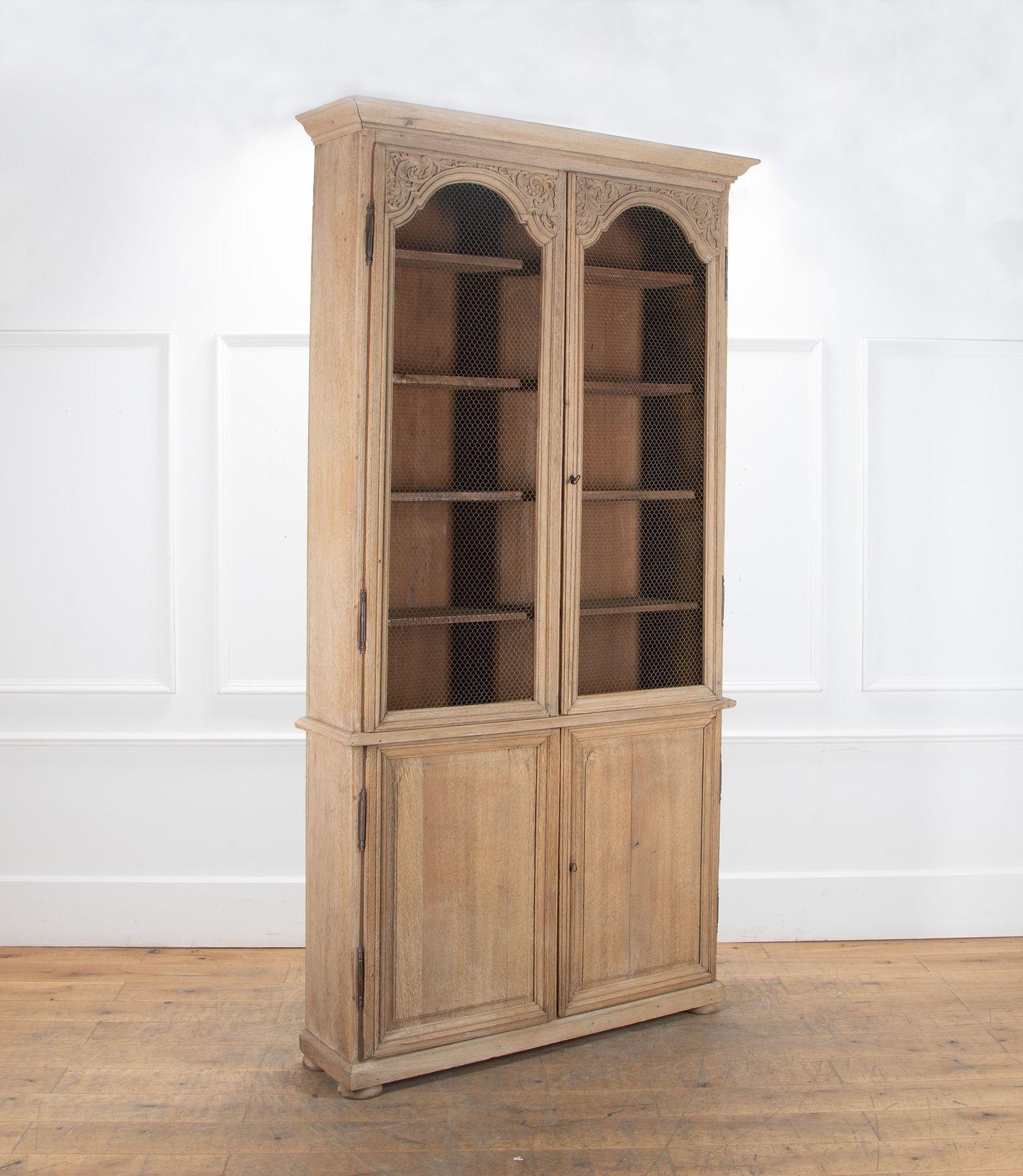 Un'alta ed elegante libreria in legno di quercia di epoca Luigi XIV, risalente all'inizio del XVIII secolo.
Con quattro ripiani fissi nella parte superiore e uno nella base.
Dettaglio intagliato a mano con finitura sbiancata sul retro.
Pannelli in