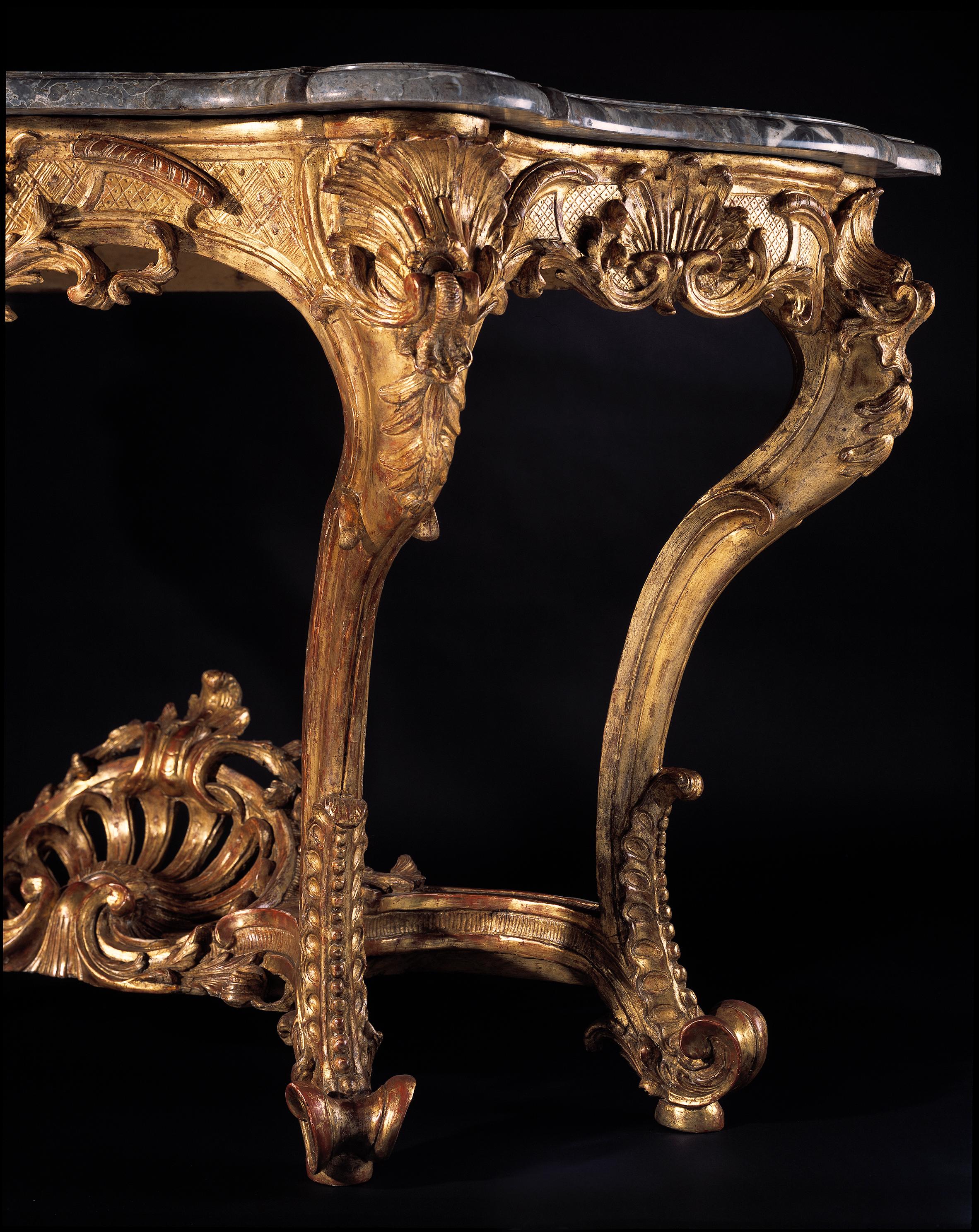 An impressive console table, the shaped, moulded grey and white marble top (Gris de Caunes moucheté) above a pierced serpentine frieze centred by a pierced c-scroll cartouche, continuing to the sides carved accordingly with c-scrolls and