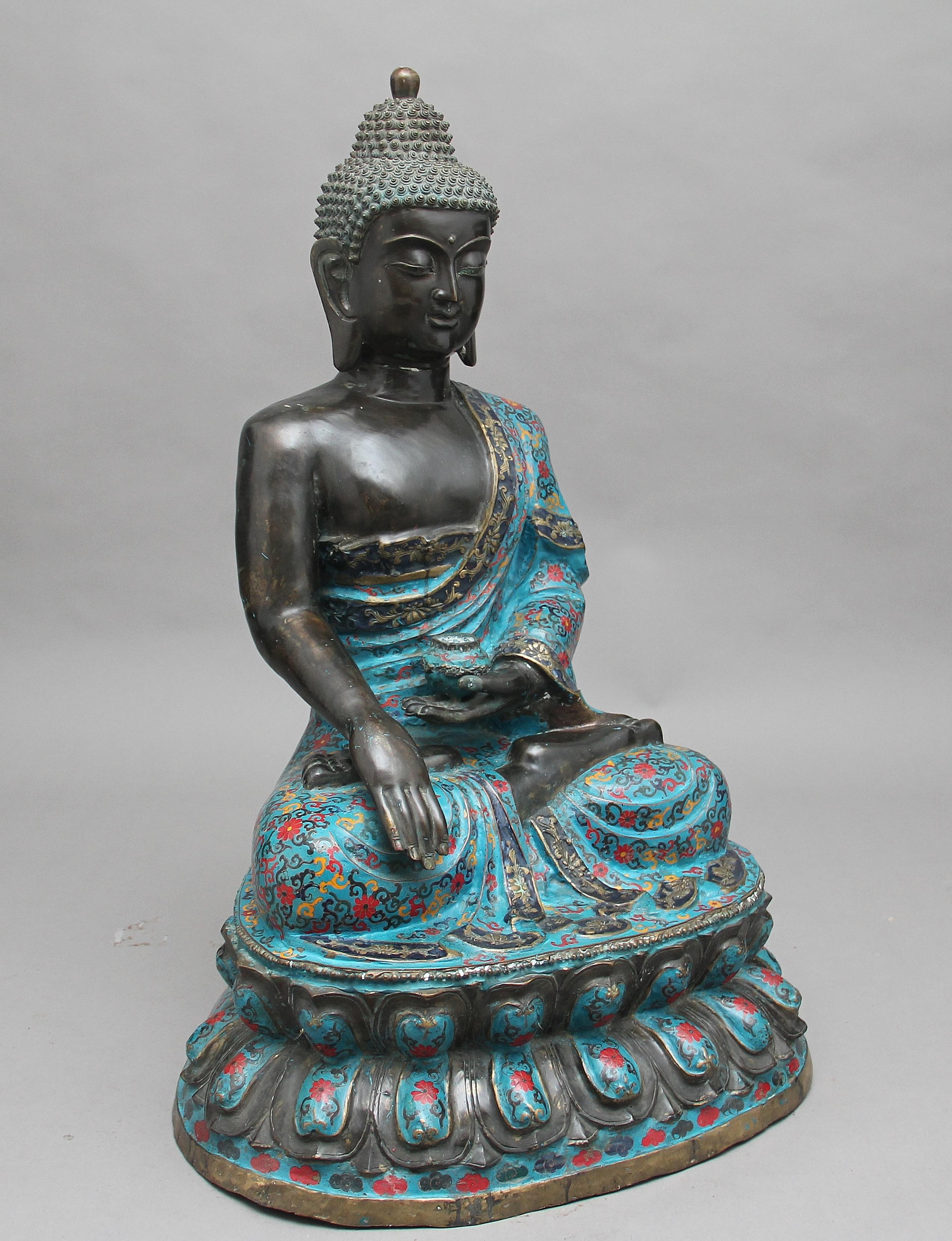 A large early 19th century bronze and cloisonné Buddha of superb quality, the seated Buddha with cloisonné enamel for the garment, with one hand holding a small cup / bowl, seated upon lotus flowers, circa 1820.
 