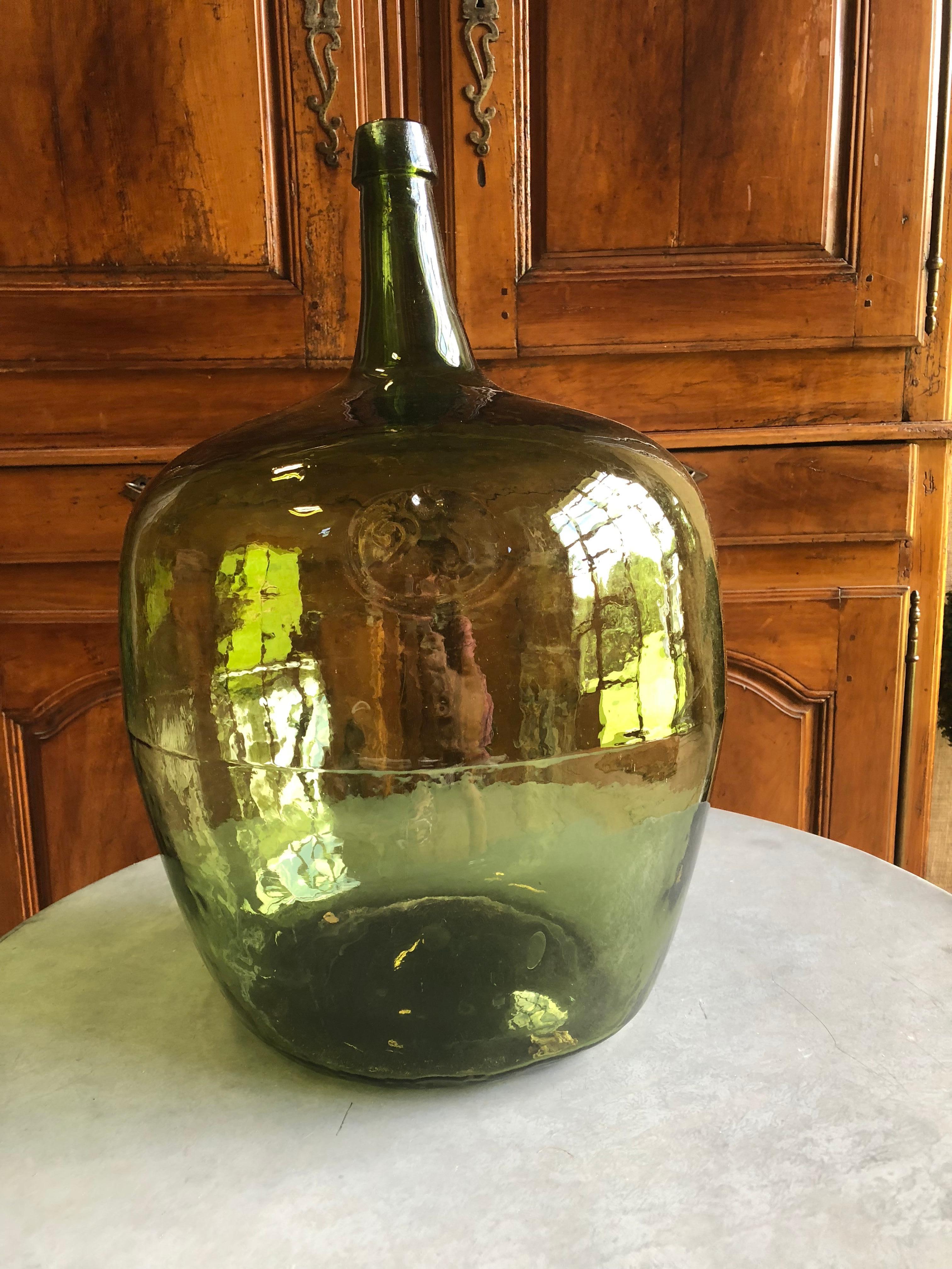 A large early 19th century green glass demijohn bottle, with an open Pontil mark on the base and impressed with the number “25” on the shoulder. Probably French, circa 1840.