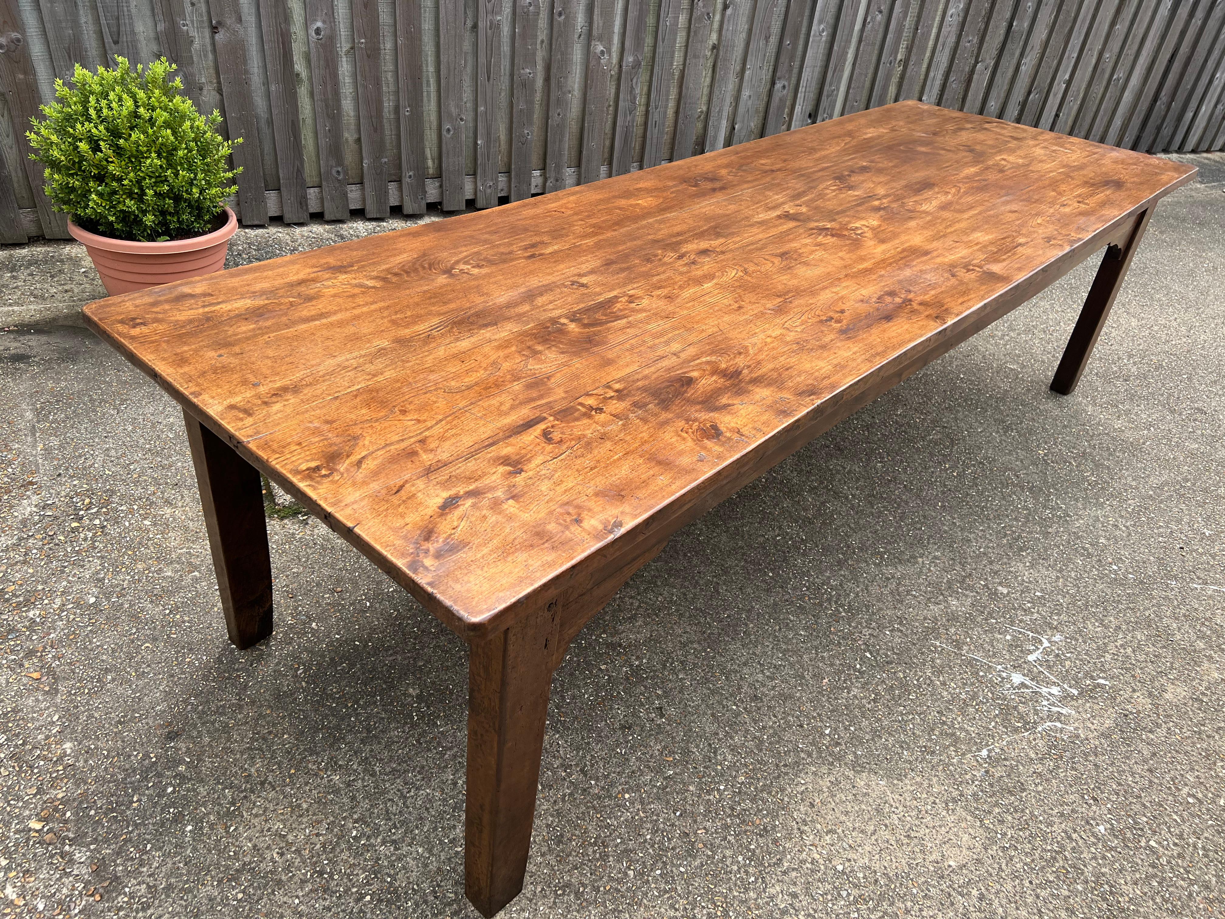 Large eearly 19th century Elm farmhouse table with wonderful patination and colour. The table has a stunning thick, four plank, figured top with one large side drawer. The table sits on a sturdy base with four chunky straight slightly inside tapered