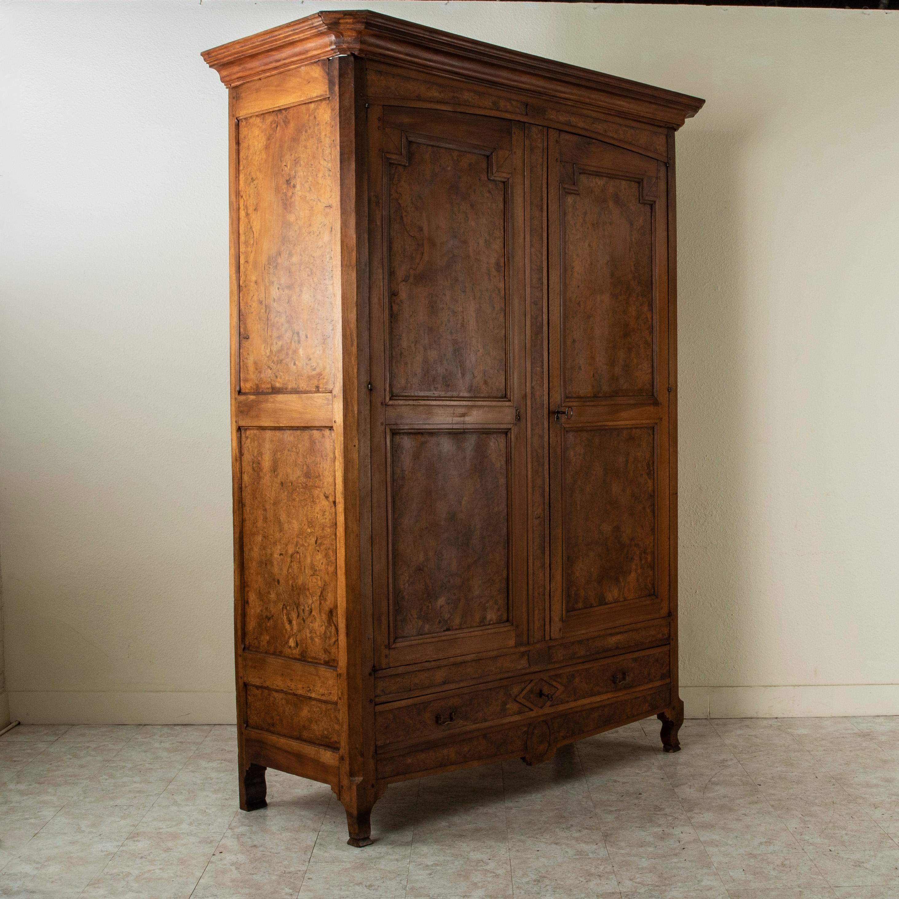 Standing at nearly 8.5 feet in height, this early nineteenth century armoire is constructed of hand begged paneled sides and doors of solid elm. It features its original hand forged iron lock and key on the right hand door and an intricately hand