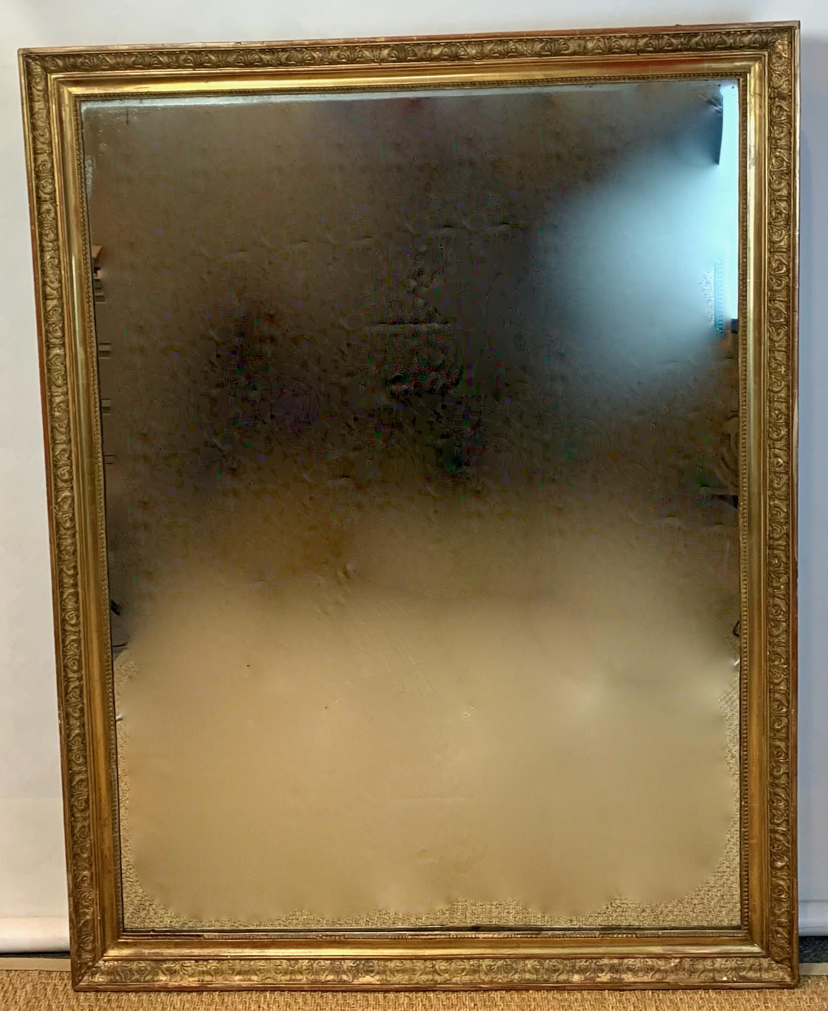 An early 19th century neoclassical French elegantly carved giltwood mirror of particularly large scale with original glass and wood back.