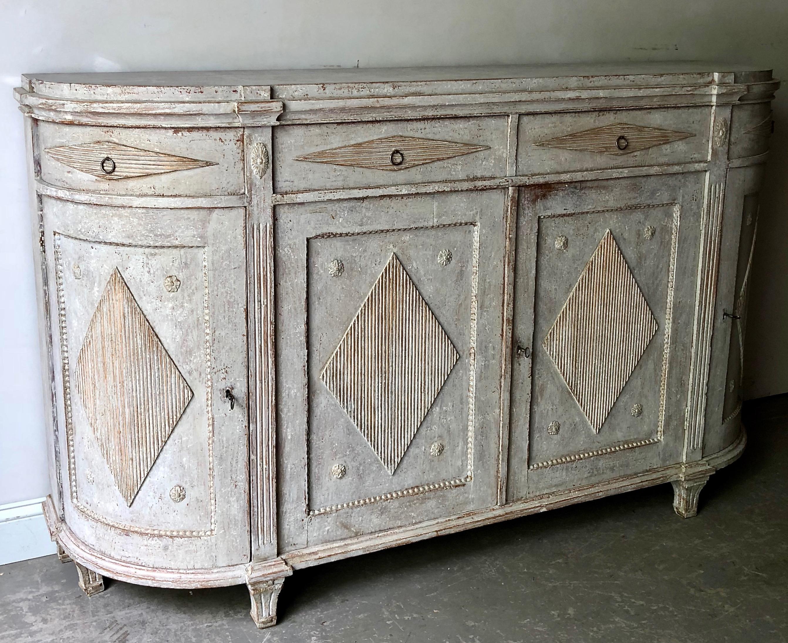 Very large, early 19th century Swedish period Gustavian sideboard in classic Gustavian manor; rounded form with reeded corner posts, four paneled doors with reeded diamond shaped lozenges and four drawers for storage, all resting on short reeded