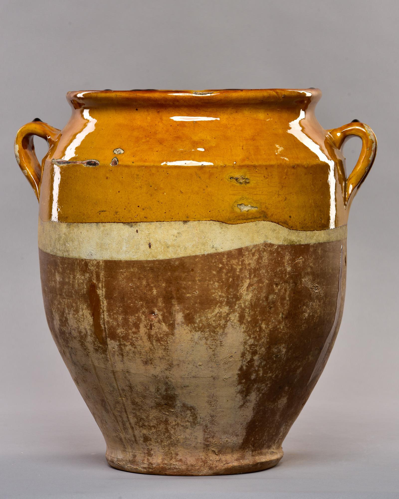Circa 1920s large French confit pot with mustard colored glaze at top and two handles. Unknown maker.
 