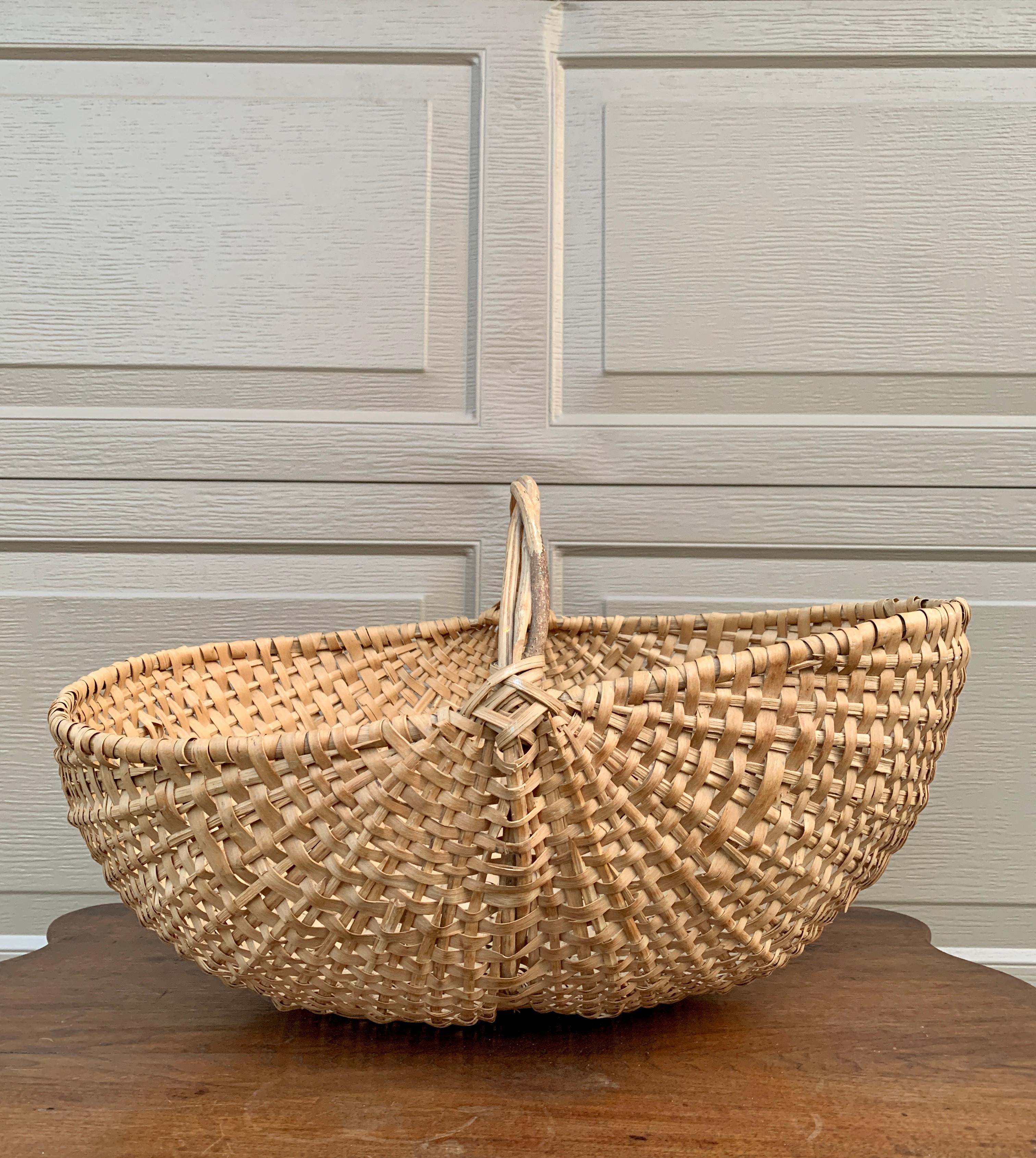A large American splint oak gathering basket with woven twig handle. The charming basket has a tight weave and would be charming as a decorative or functional piece.

USA, Early 20th Century

Measures: 22.75